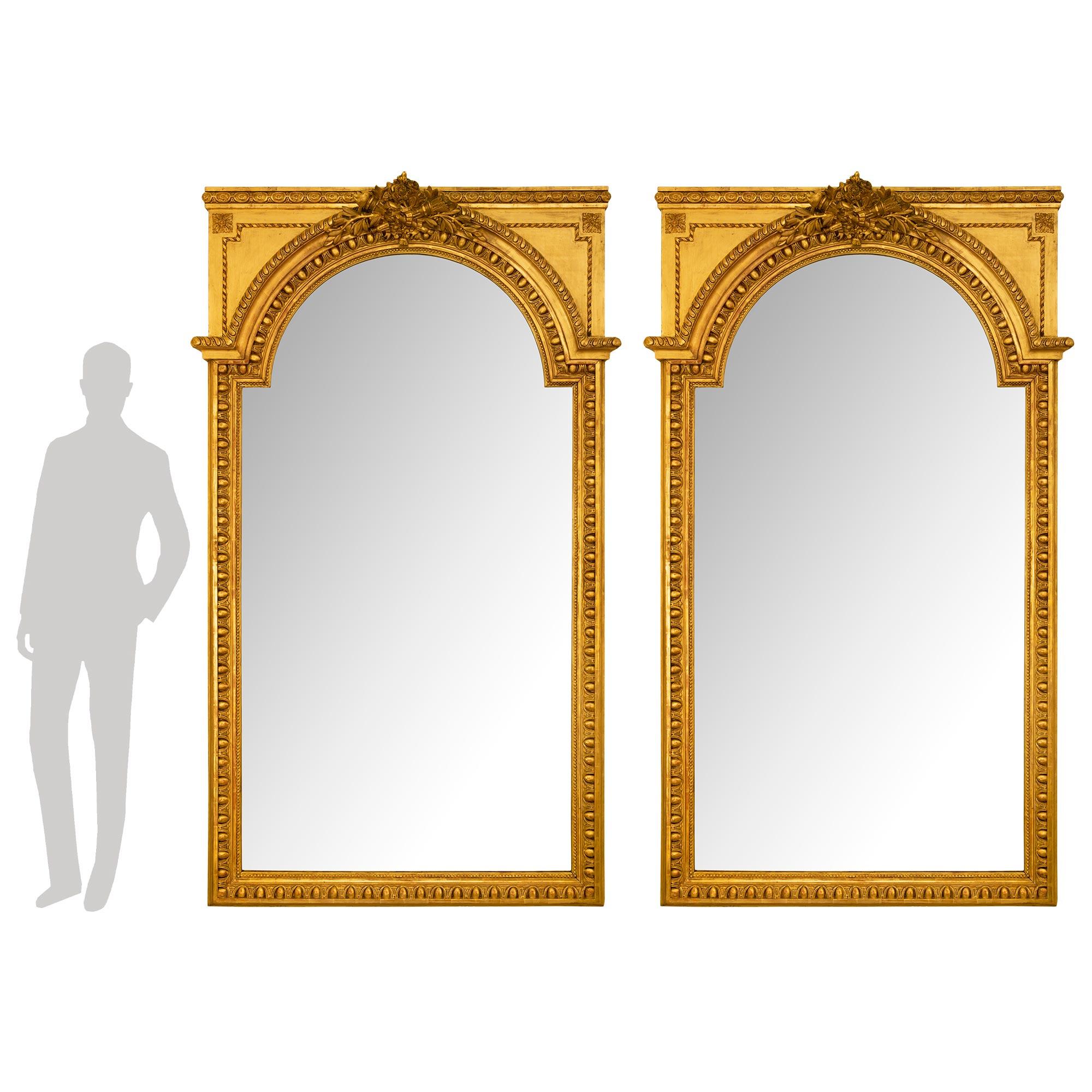 Superbe paire de miroirs en bois doré de style Louis XVI, datant du milieu du XIXe siècle. Chaque miroir conserve sa plaque d'origine encadrée d'une élégante bordure perlée chinée. Le cadre présente un exceptionnel et très décoratif motif d'œuf et