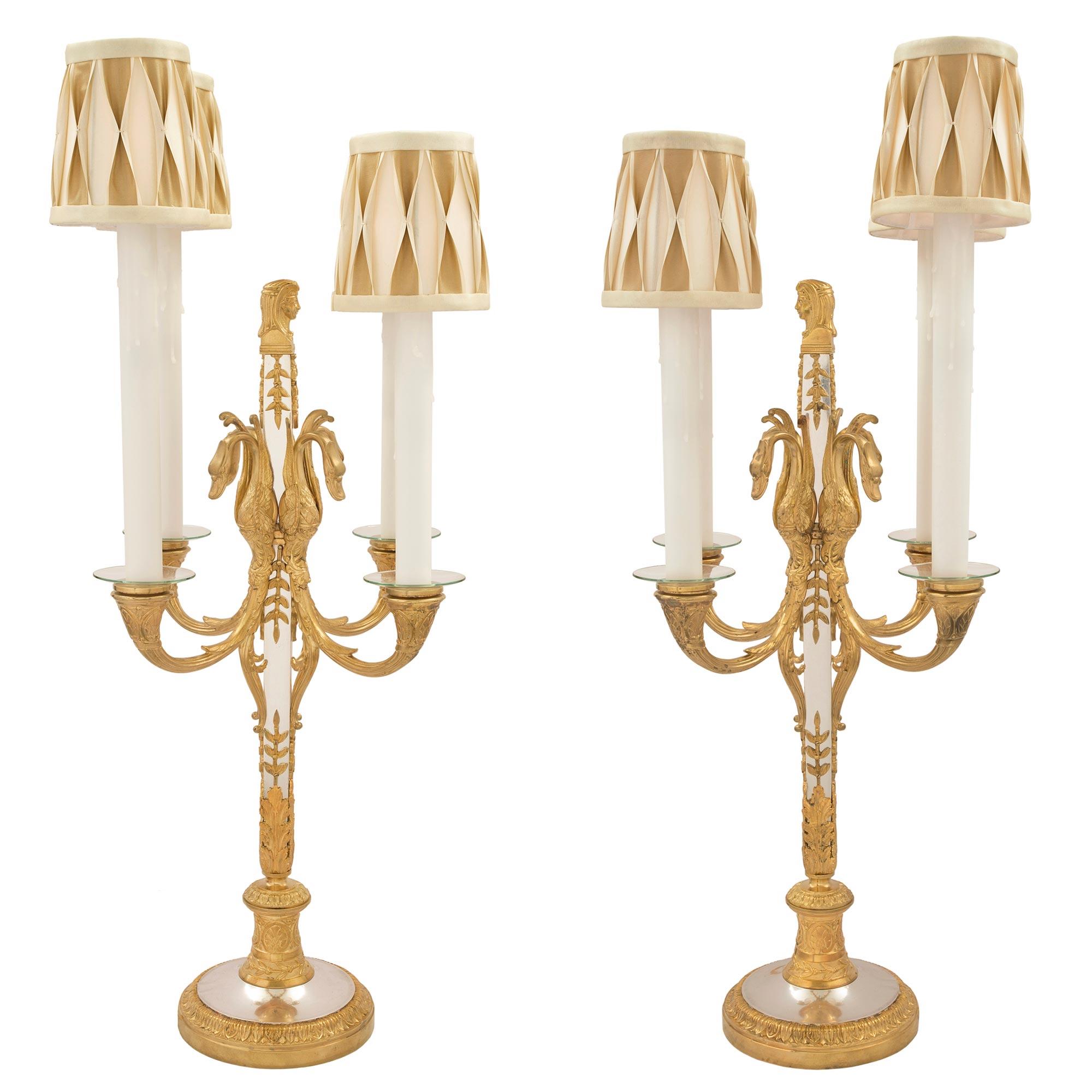 A sensational and most elegant pair of French mid 19th century Neo-Classical st. four arm electrified candelabras in ormolu and silvered bronze. The pair are raised by circular ormolu bases with a mottled edge and a Coeur de Rai design. Above is the