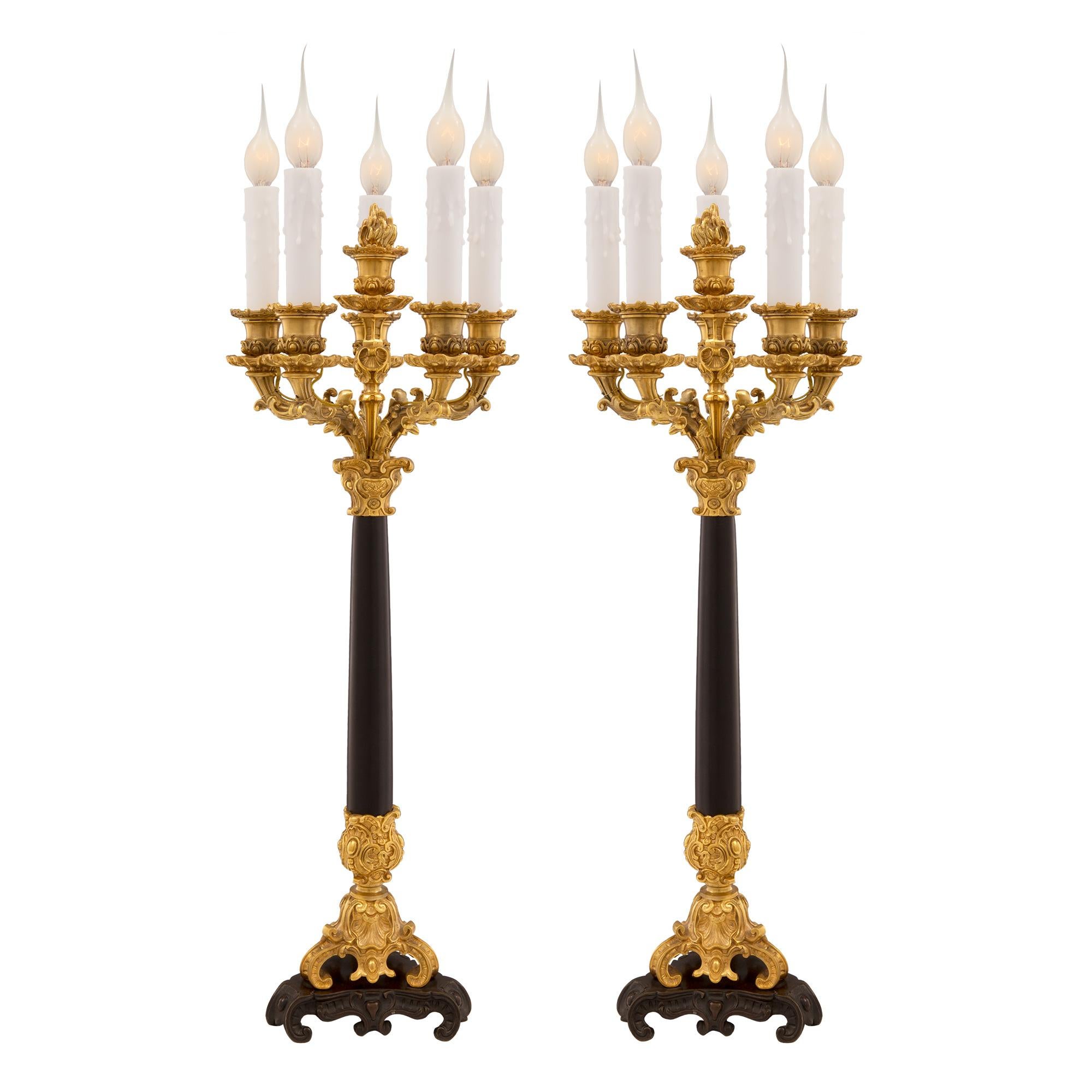Una coppia di lampade a candelabro a cinque bracci in bronzo patinato, ormolu e marmo nero belga, di grande effetto e di alta qualità, risalenti alla metà del XIX secolo. Ogni lampada è sollevata da una base triangolare a gradini in bronzo patinato