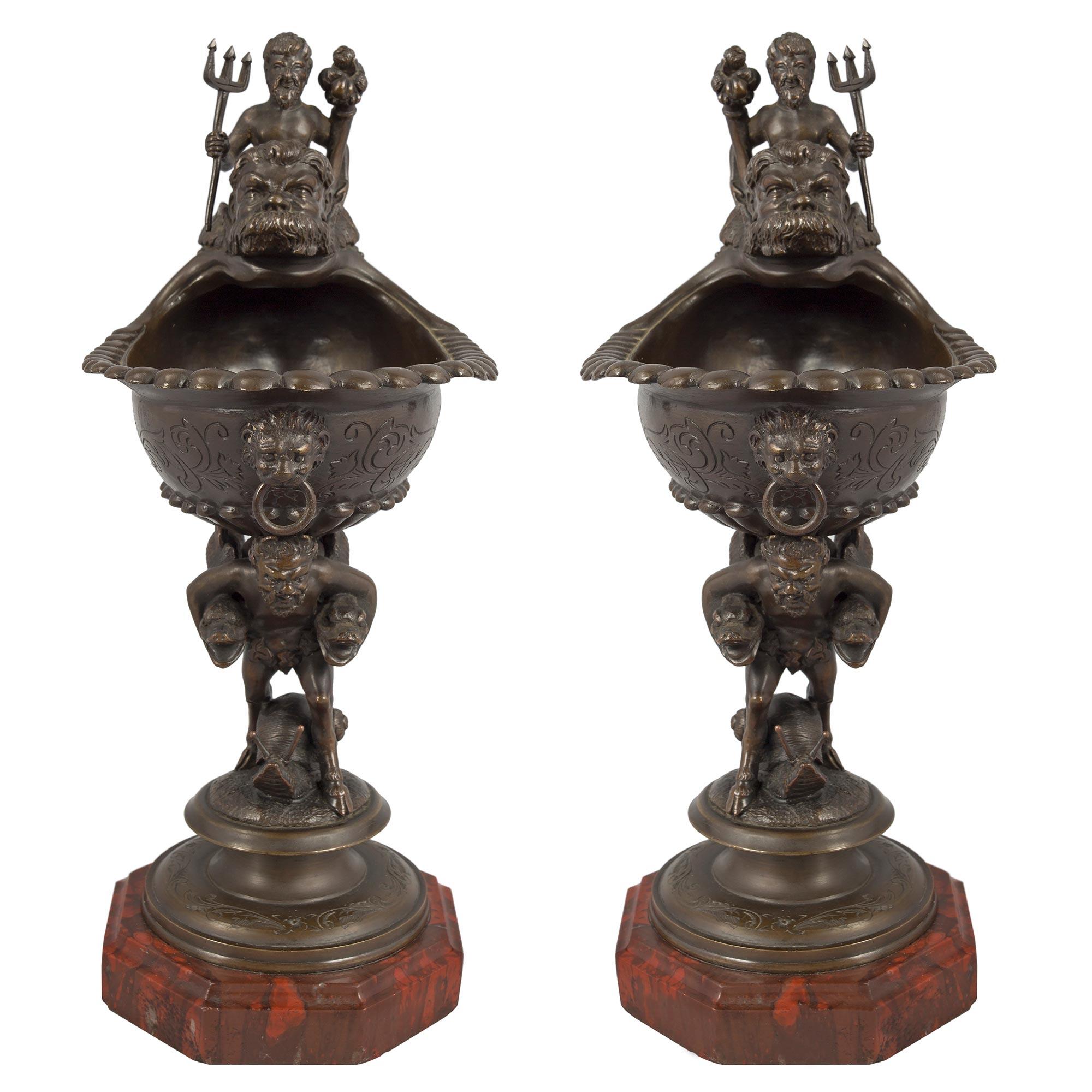 A most decorative and highly detailed pair of French mid 19th century Renaissance st. patinated bronze and Rouge Griotte marble ewers. The pair are raised by octagon shaped Rouge Griotte marble bases with a mottled top border. Above is the circular