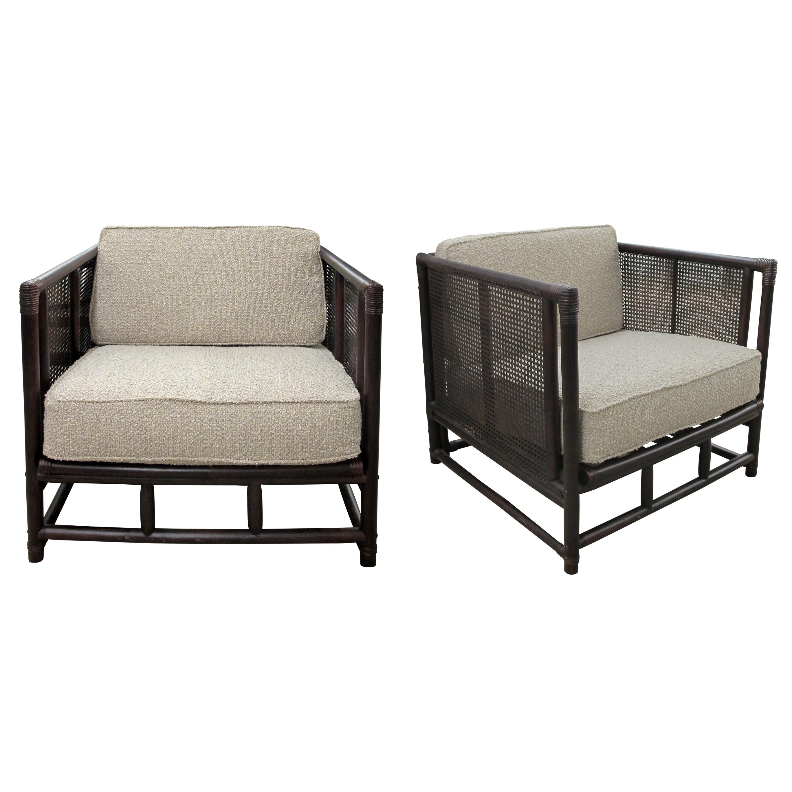Pair of French mid-century large structural armchairs made from bamboo and rattan, reflecting the timeless elegance of mid-20th-century aesthetics. The frames feature a dark brown finish, emphasising the natural texture of the materials. The