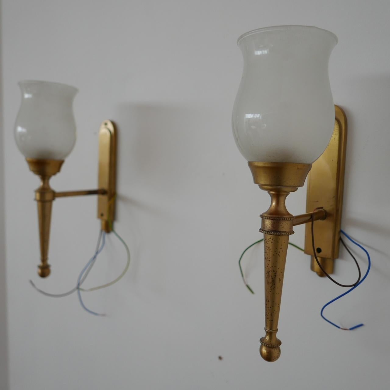 A pair of simple but elegant brass and glass wall lights.

France, circa 1960s.

Naturally patinated brass wall galleries, slightly opaque shades.

Re-wired and PAT tested.

Location: Belgium Gallery.

Dimensions: 30 H x 9 W x 16 D in