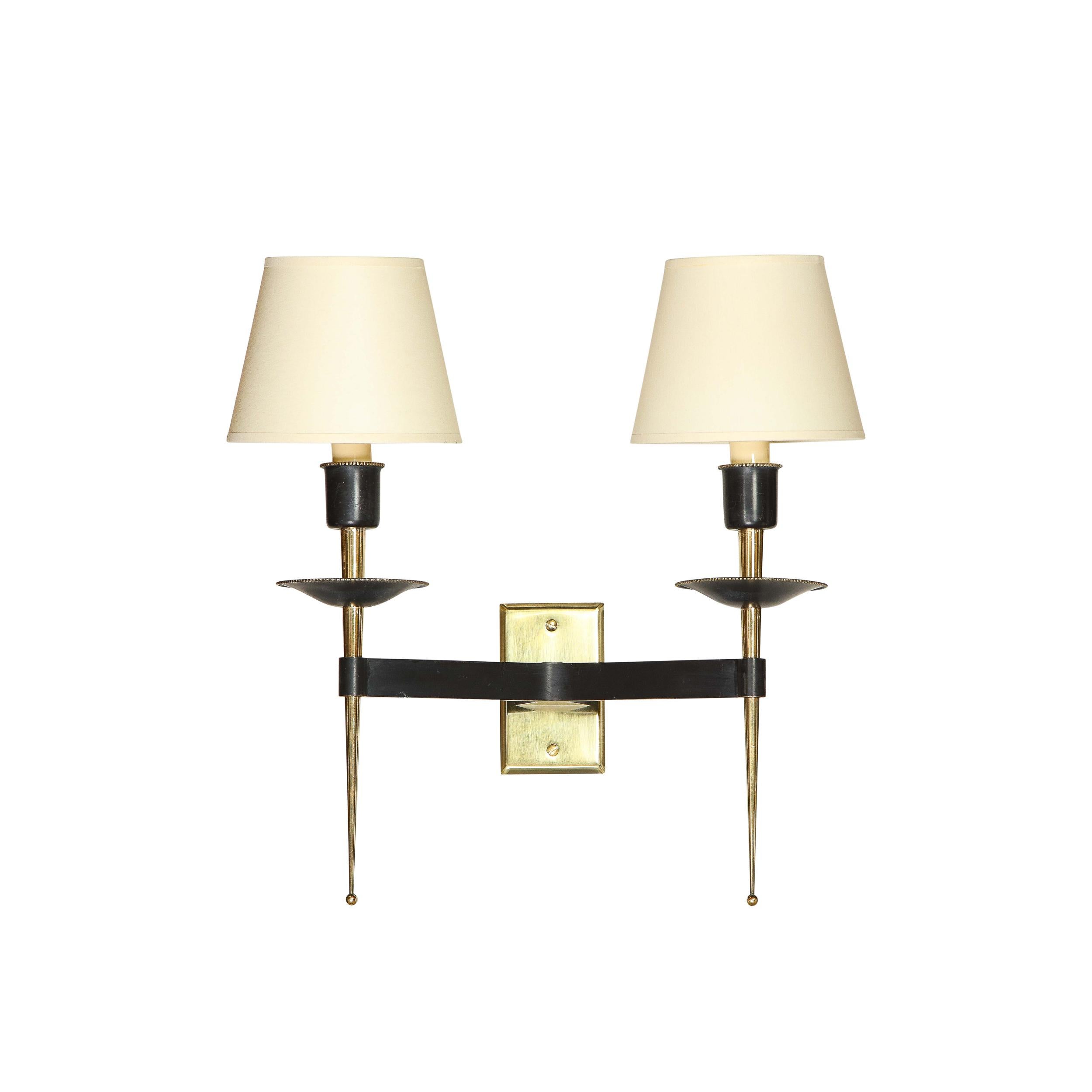 This stunning and graphic pair of Mid-Century Modern sconces were realized in France, circa 1950. They feature cylindrical brass bodies that attach to a rectangular polished brass back plate via two sculptural black enamel supports. This black
