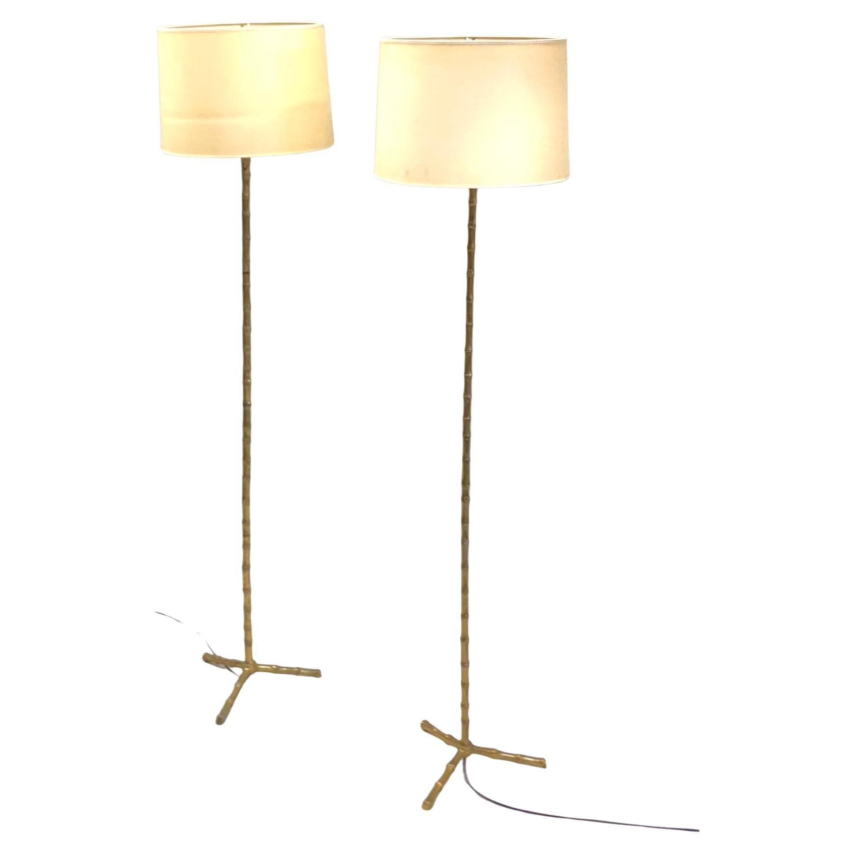 An Elegant and Timeless Pair of French Mid-Century Modern Neoclassical Floor Lamps by Maison Bagues in Solid Brass Faux Bamboo. The pieces feature a rare flattened, thick tripod bases supporting thick faux bamboo stems. The whole composition was a