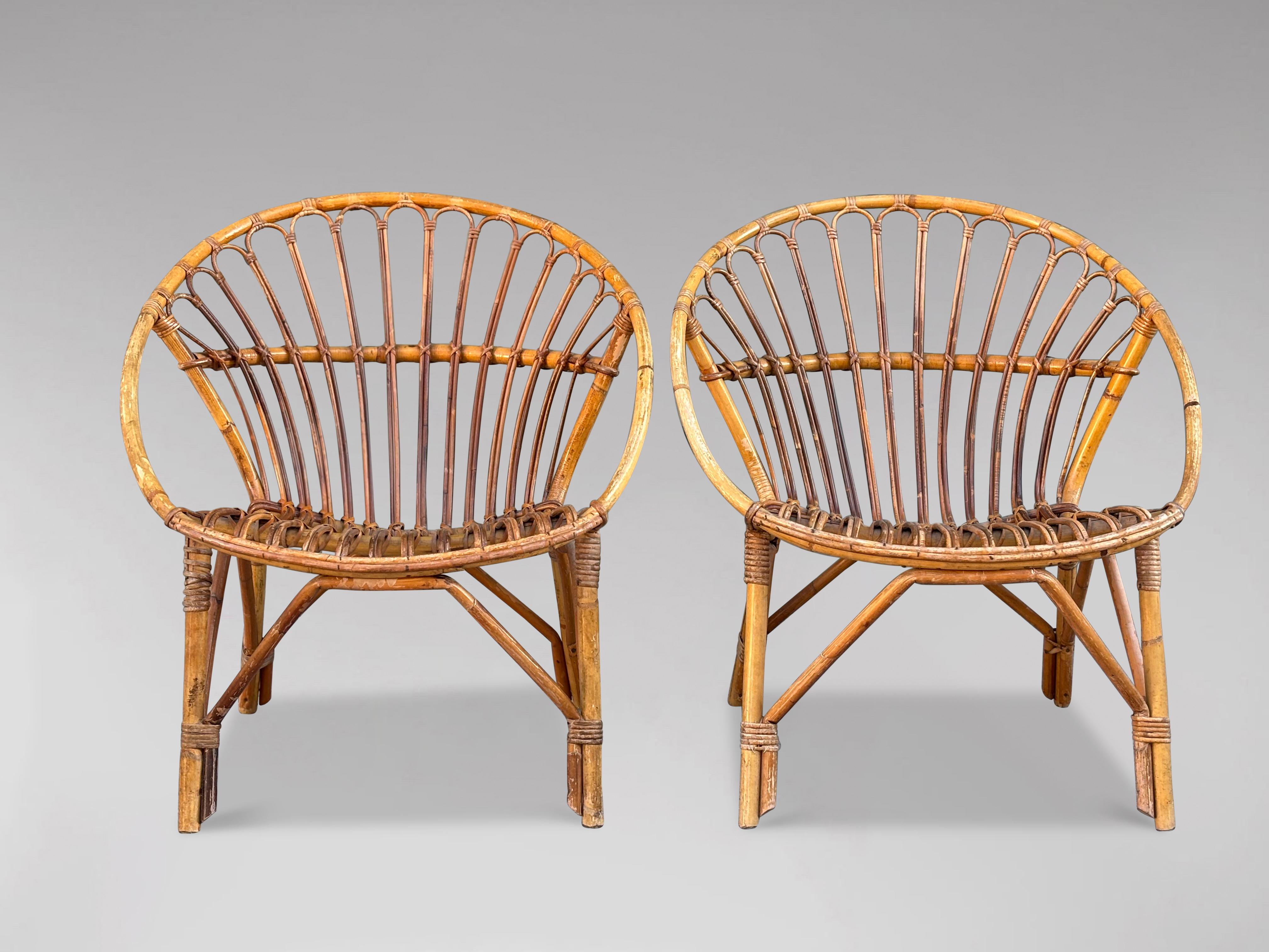 Cette paire de chaises longues en bambou et rotin de la Côte d'Azur du milieu du XXe siècle présente un cadre circulaire en bambou et du rotin tissé à la main. Le design est à la fois élégant et exceptionnellement confortable, ce qui en fait un