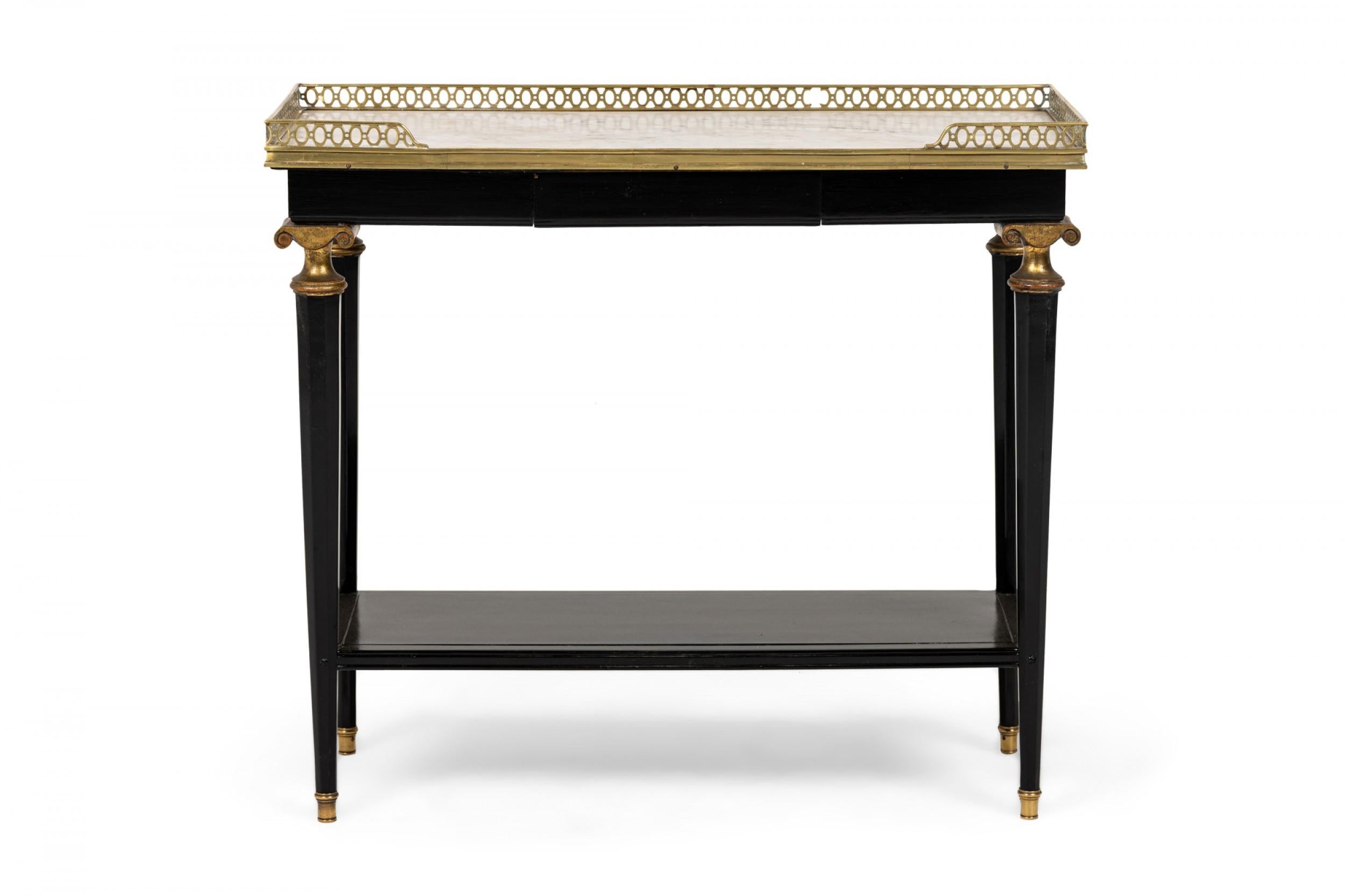 Pair of French mid-century (circa 1950) rectangular ebonized end / side tables with brass scroll capital design mounts under white marble tops surrounded with a filigree gallery, and a lower stretcher shelf connecting four tapered and faceted legs