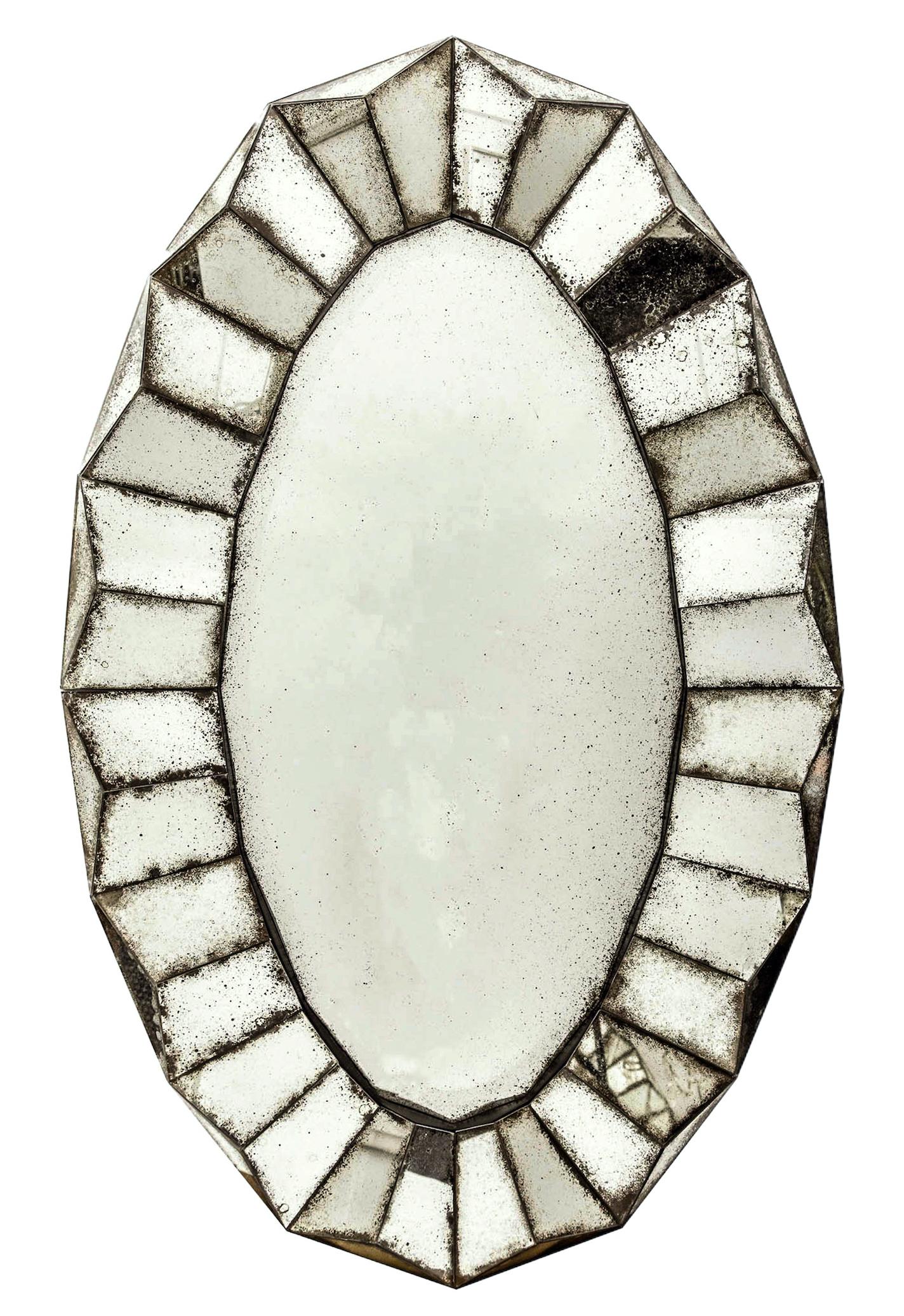 This pair of large faceted oval mercury glass mirrors from France was made in the 1940’s . Each of the large oval mirrors is framed by 48 pieces of cut mercury glass mirror mounted on sculpted wood base. The passage of time has enhanced patina of