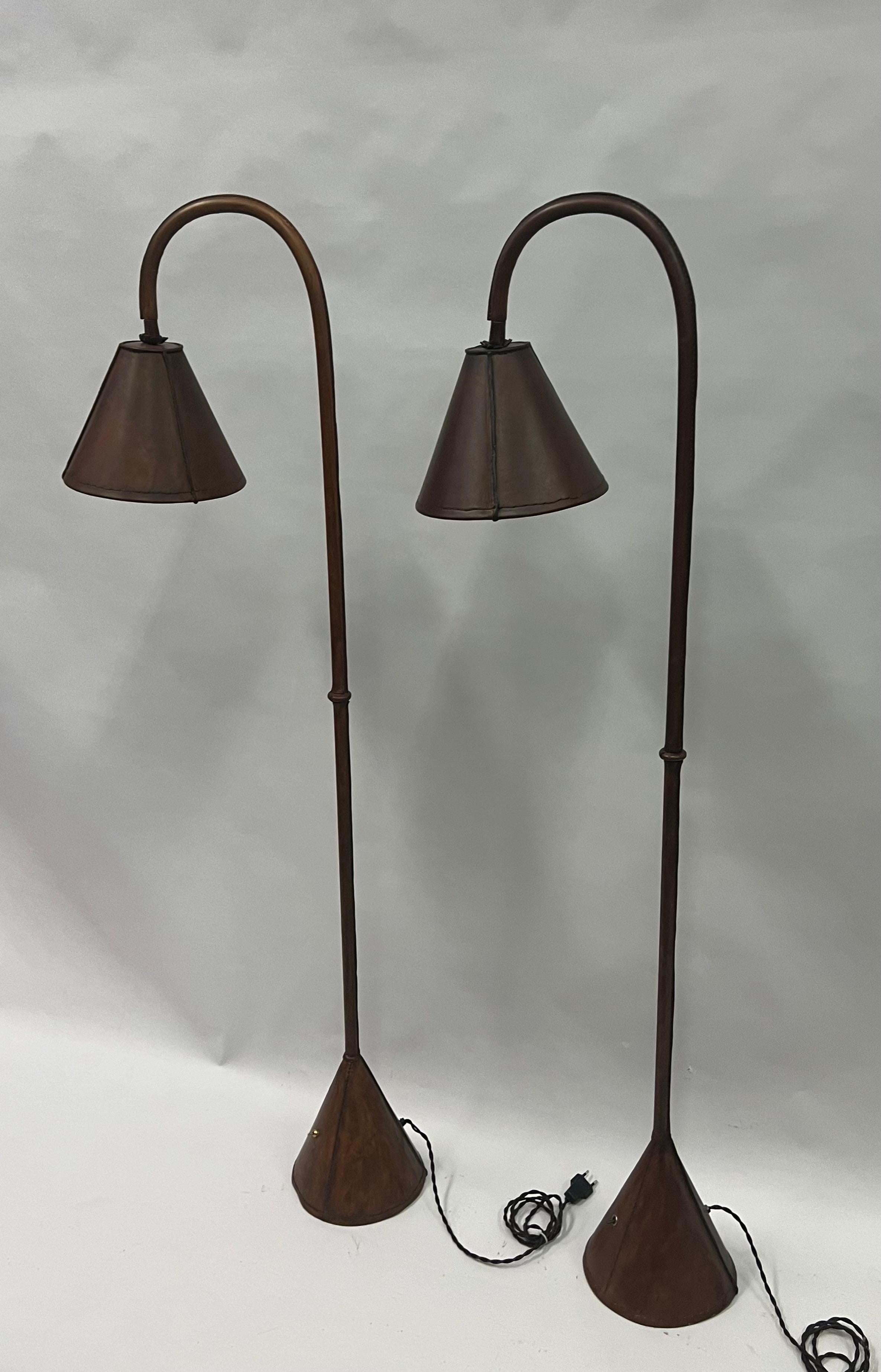 Elegant and Timeless Pair of French Mid-Century Modern Hand-Stitched Dark Brown Leather Floor Lamps by Jacques Adnet circa 1950. This classic hand made model from the renowned French designer, Jacques Adnet is sought after as an icon of design and