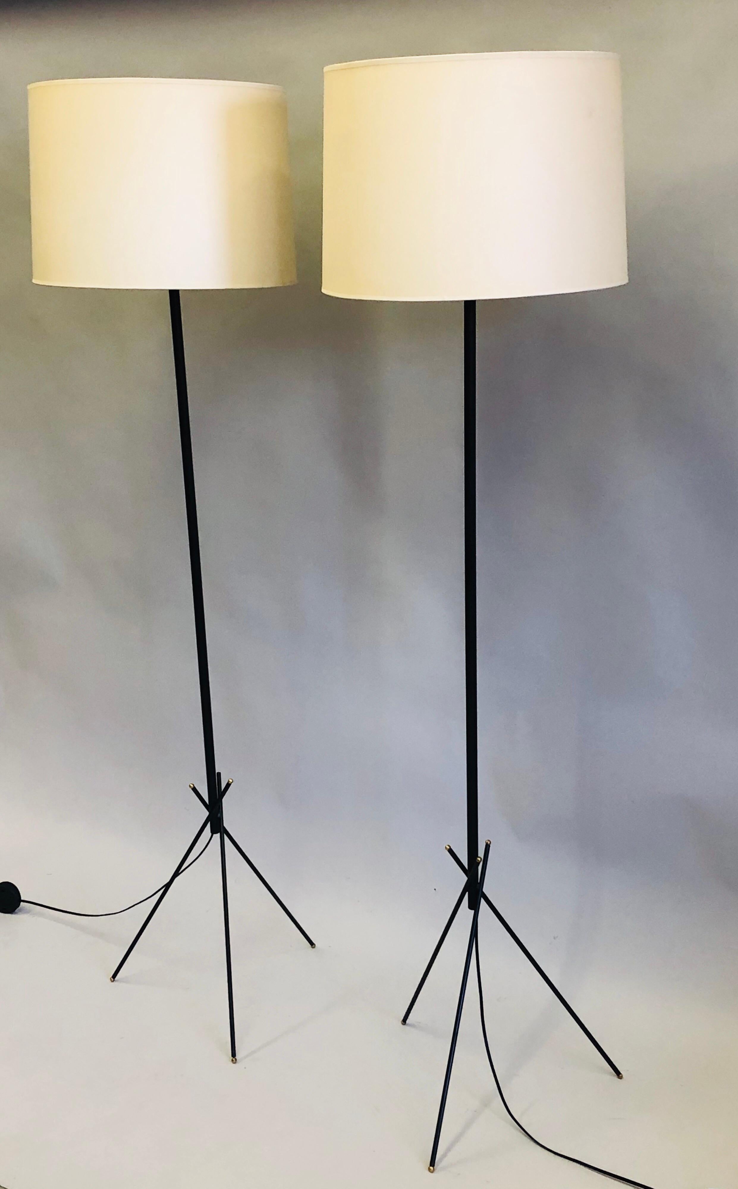 Elegant, pair of French Mid-Century Modern floor lamps in enameled wrought iron with brass ball details attributed to Disderot, circa 1950-1960. The standing lamps are set upon a stunning, architectural base composed of 3 round iron rods that