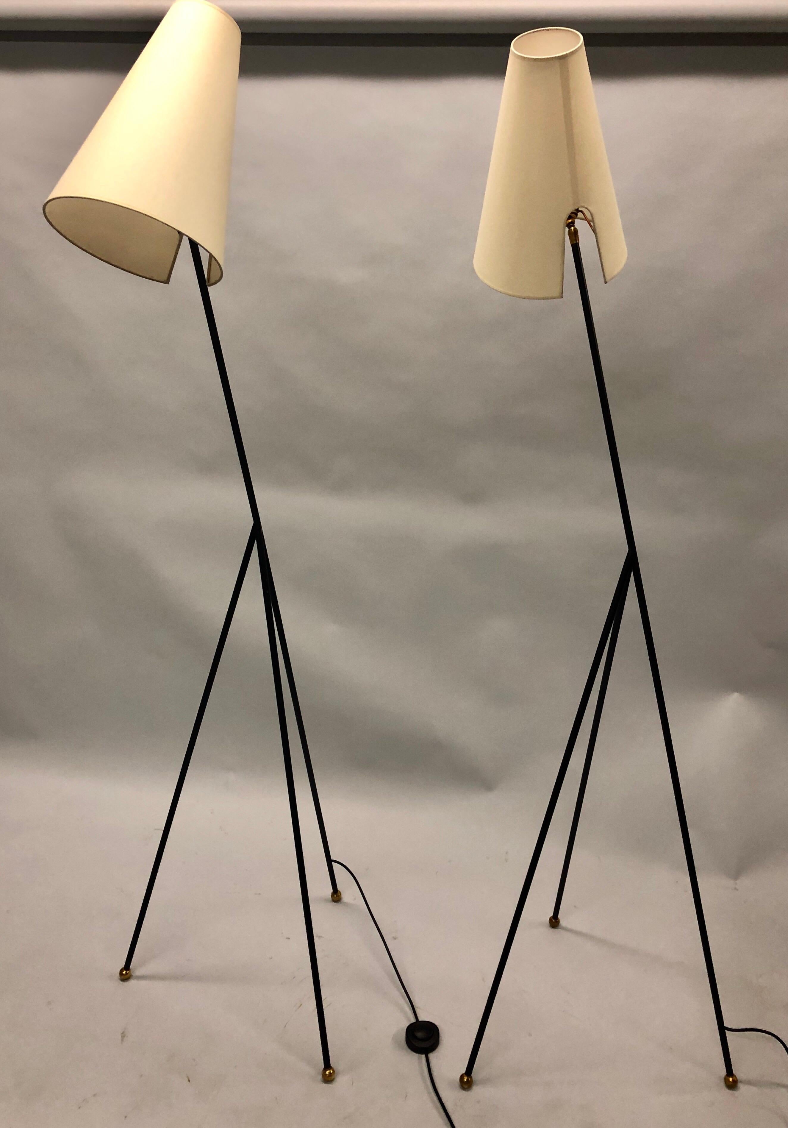 Elegant, sculptural pair of French Mid-Century Modern enameled wrought iron floor lamps attributed to Disderot
 
The standing lamps have a stunning triangulated form, elegant tapered legs terminating in brass ball finials and finished with conical