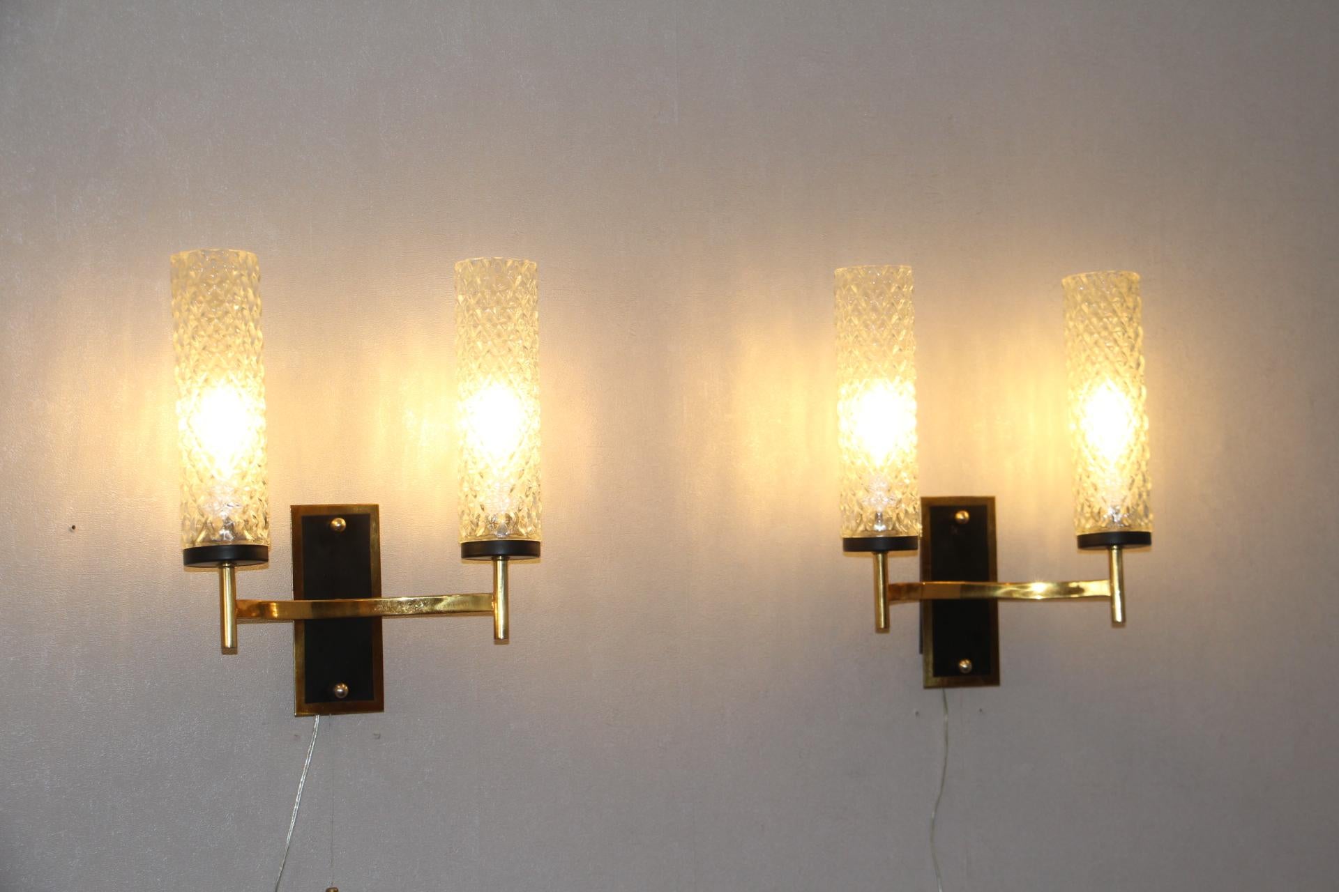 This beautiful pair of French midcentury sconces, in the style of Maison Arlus and Lunel, features textured glass tubes on a black lacquered steel back plate with brass details and switch. Perfect working order.
They are very elegant with a kind of