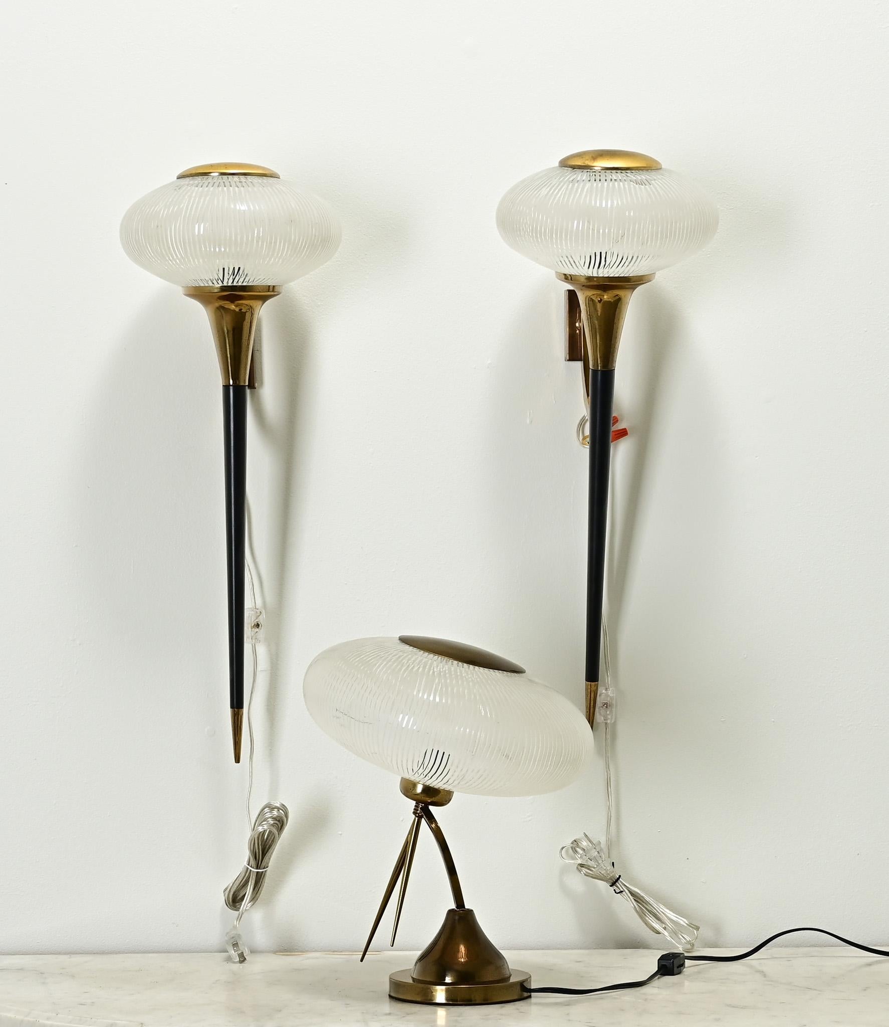 An impressive collection of a pair of sconces and a table lamp made in Mid-Century France. The fixtures each have a round brass plate at the top that is removable for changing a single light bulb. The bulbous etched glass globes are whimsical and