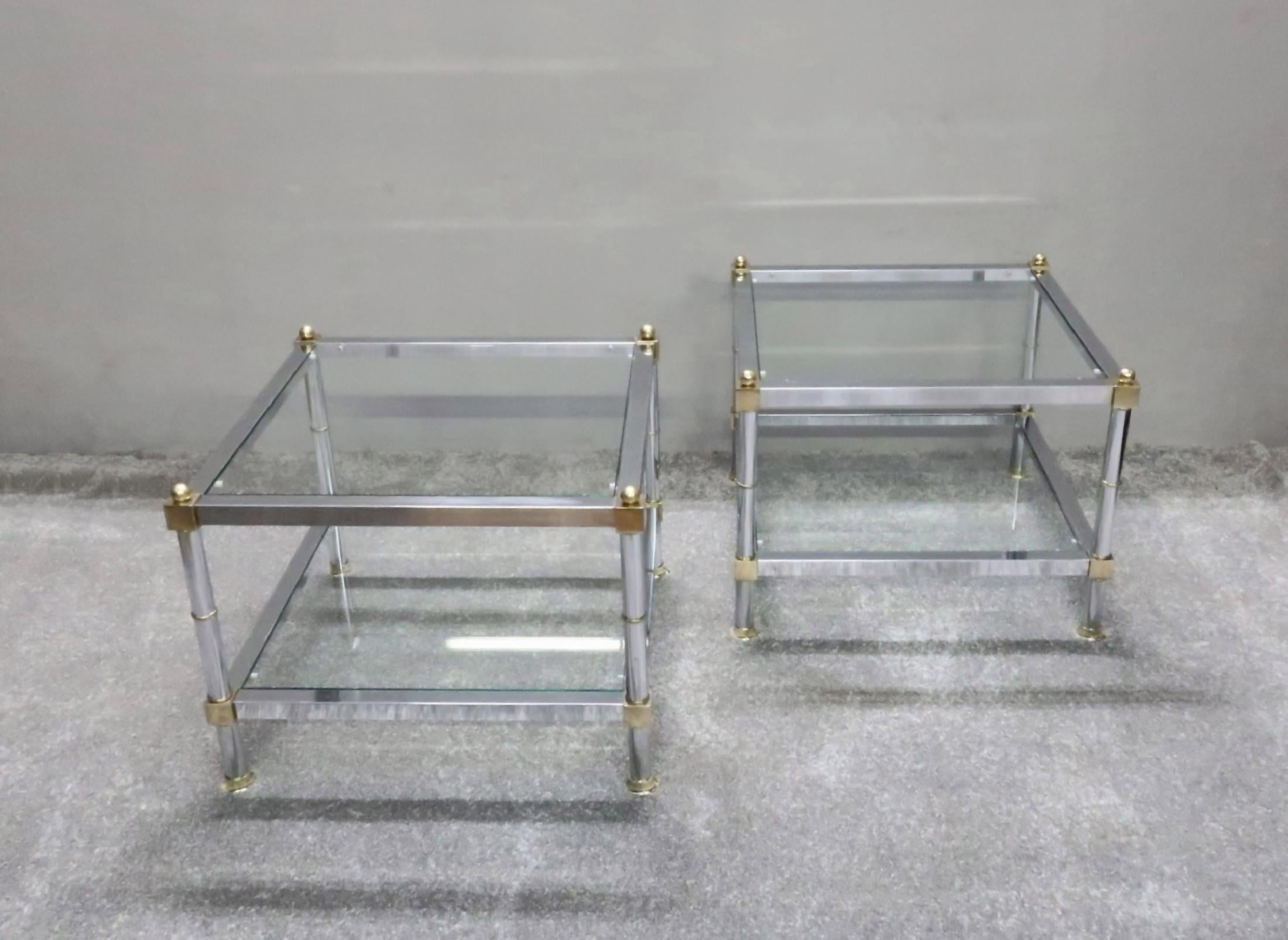 A pair of French Mid-Century Modern chrome side or end tables with square frame and tubular column legs with brass rings, feet and ball finials to the top in the manner of Maison Jansen. Each table has two new toughened inset clear glass shelves.
 
