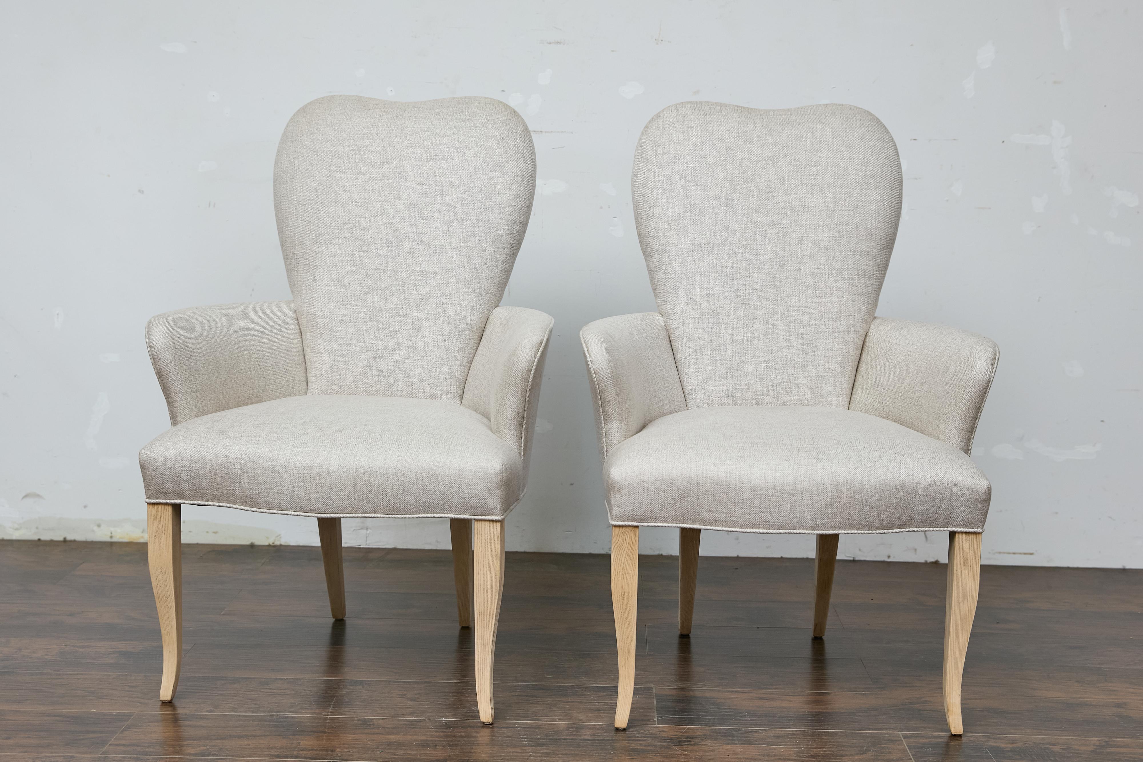A pair of French Midcentury armchairs with natural tapering legs and custom linen upholstery. This pair of French Midcentury armchairs charms us with its graceful lines and custom linen upholstery, offering a perfect blend of comfort and style. The