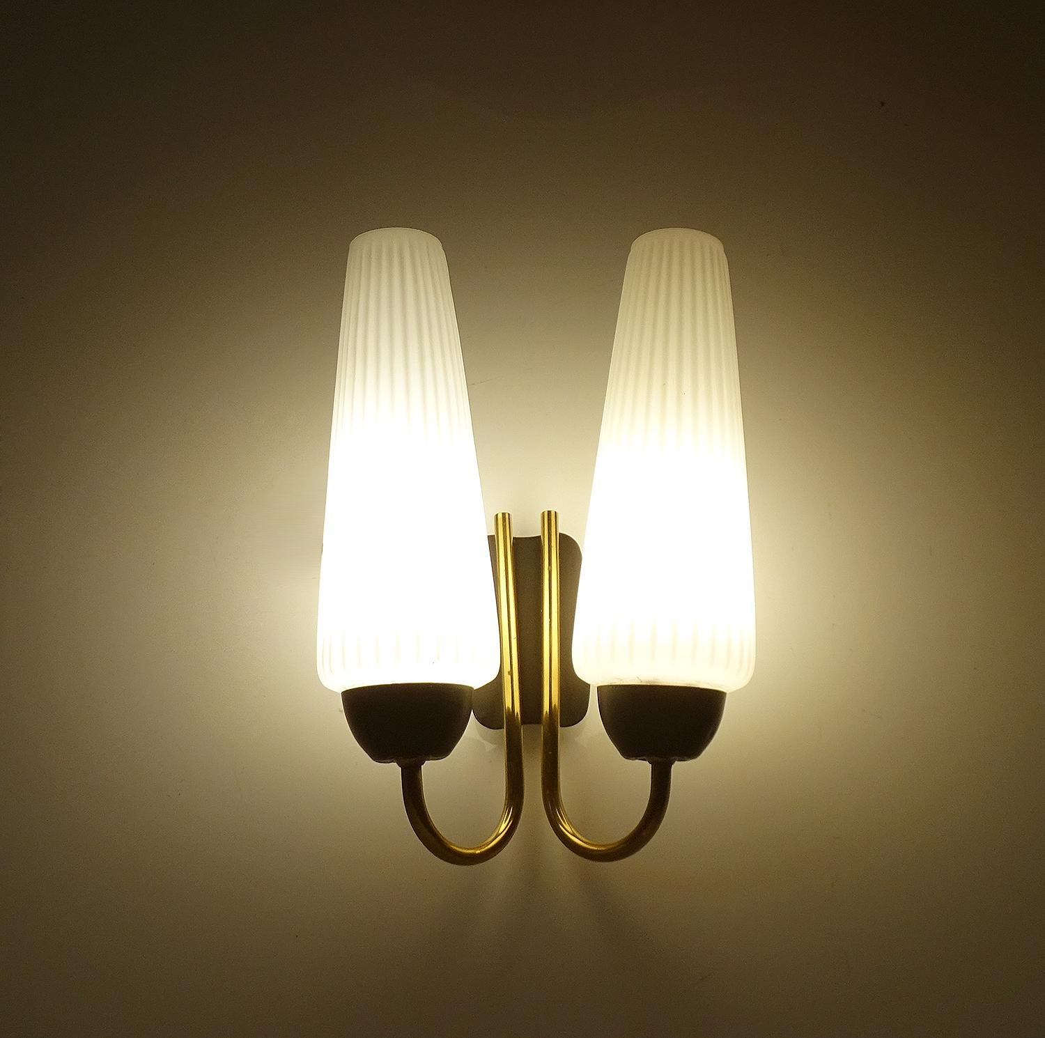 Pair of 1960s French midcentury sconces featuring two conical ribbed opaline glass shades mounted on a sinuous double brass and black enameled structure
Dimensions
H 9.85 in. x W 7.09 in. x D 3.94 in.
H 25 cm x W 18 cm x D 10 cm
Two candelabra size