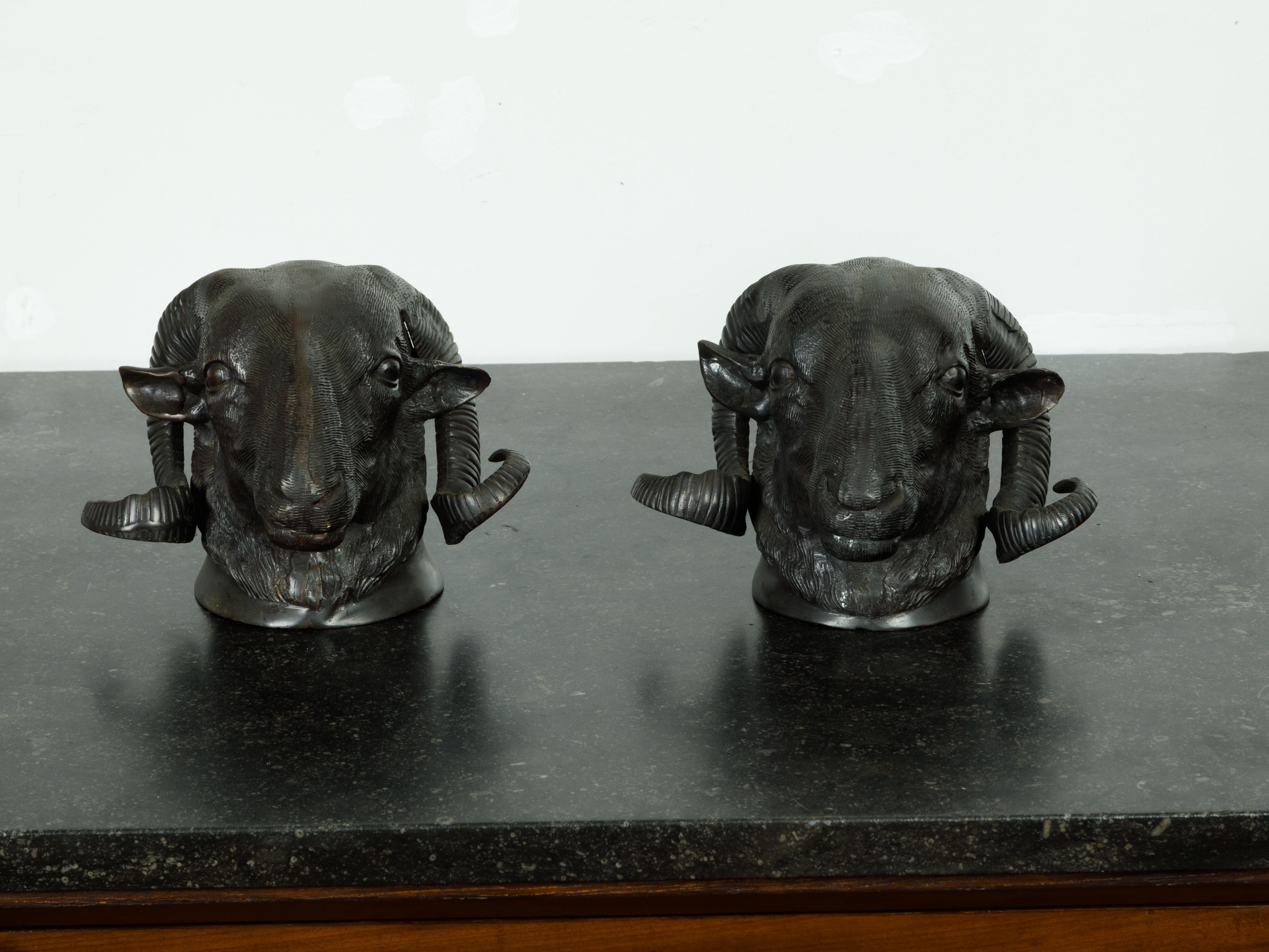 A pair of French bronze rams' heads from the mid 20th century, with dark patina. We currently have two pairs available, priced and sold $2,250 each pair. Created in France during the midcentury period, each of this pair of bronze sculptures features