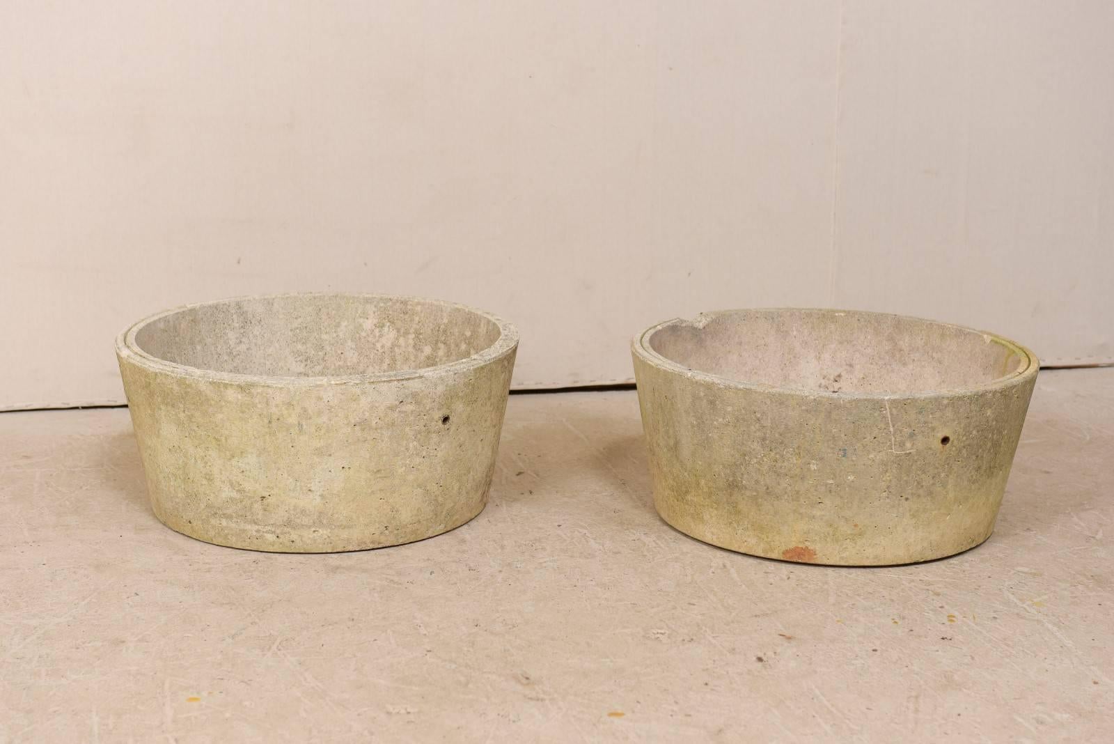 A pair of French cast concrete pots from the mid-20th century. This pair of vintage French pots, with their simplistic designs, feature round-shaped bodies which have a subtle taper towards their base. The pots are over 2 ft wide, and each have a