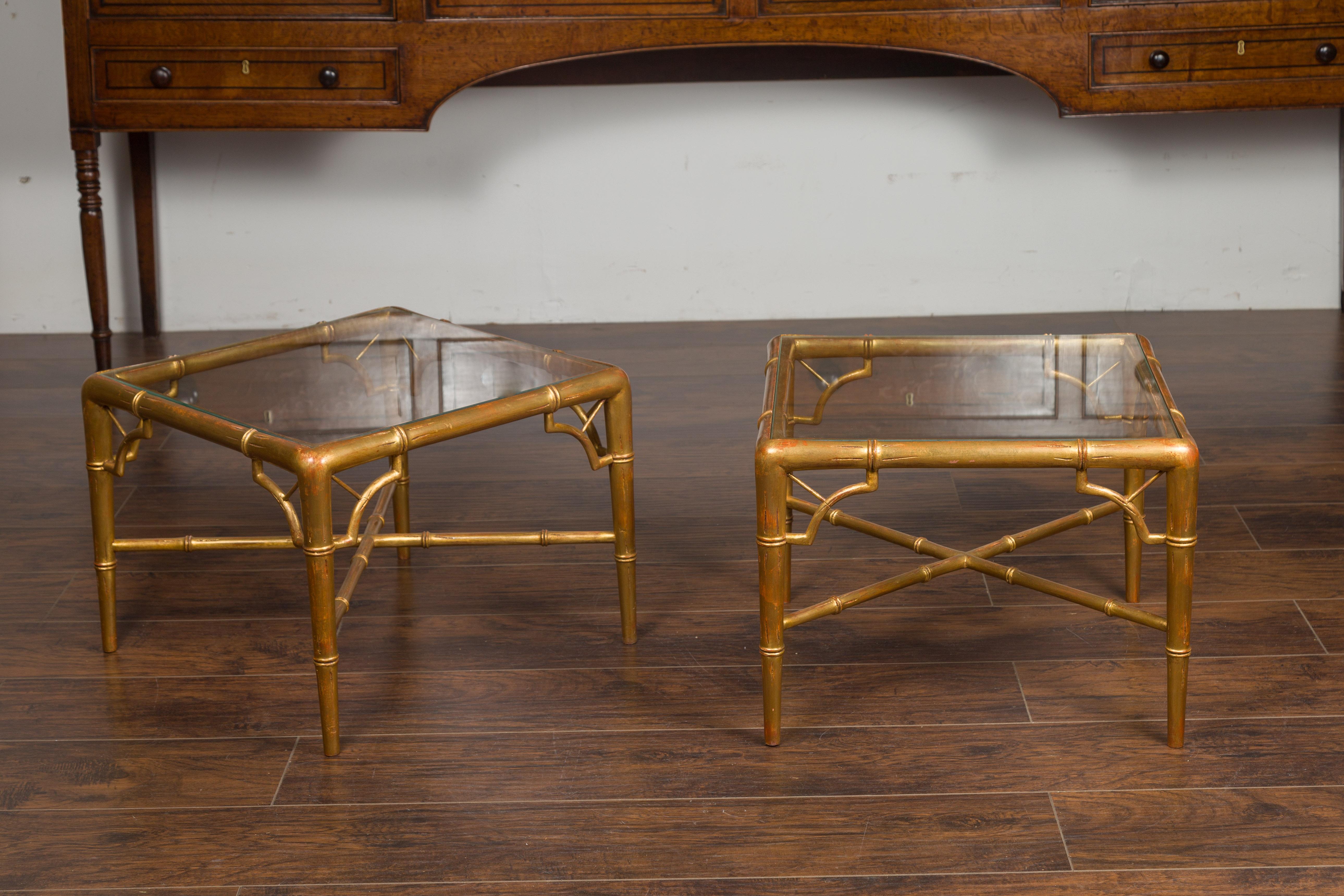 A pair of French vintage gilt faux bamboo drinks tables from the mid-20th century, with glass tops and X-form cross stretchers. Created in France during the midcentury period, each of this pair of drinks tables features a gilt faux bamboo structure