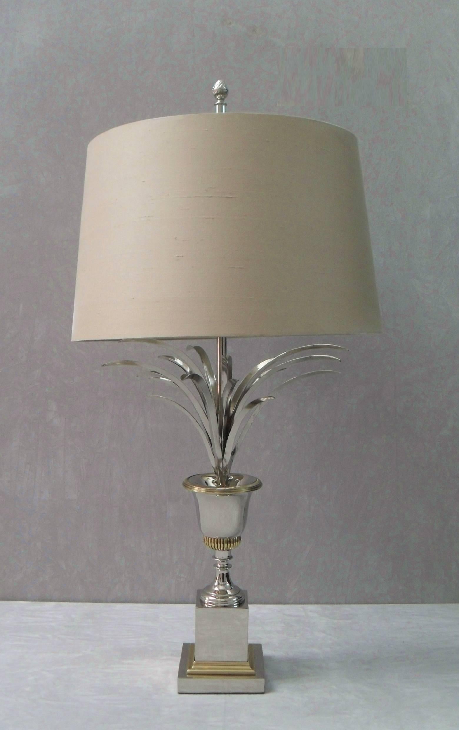 An elegant pair of French Mid-Century Modern polished nickel plated and brass 'Vase Roseaux' table lamps in the style of Maison Charles. The lamps have three tiers of formed leaves within an urn stood on a square pedestal and square plinth bass with