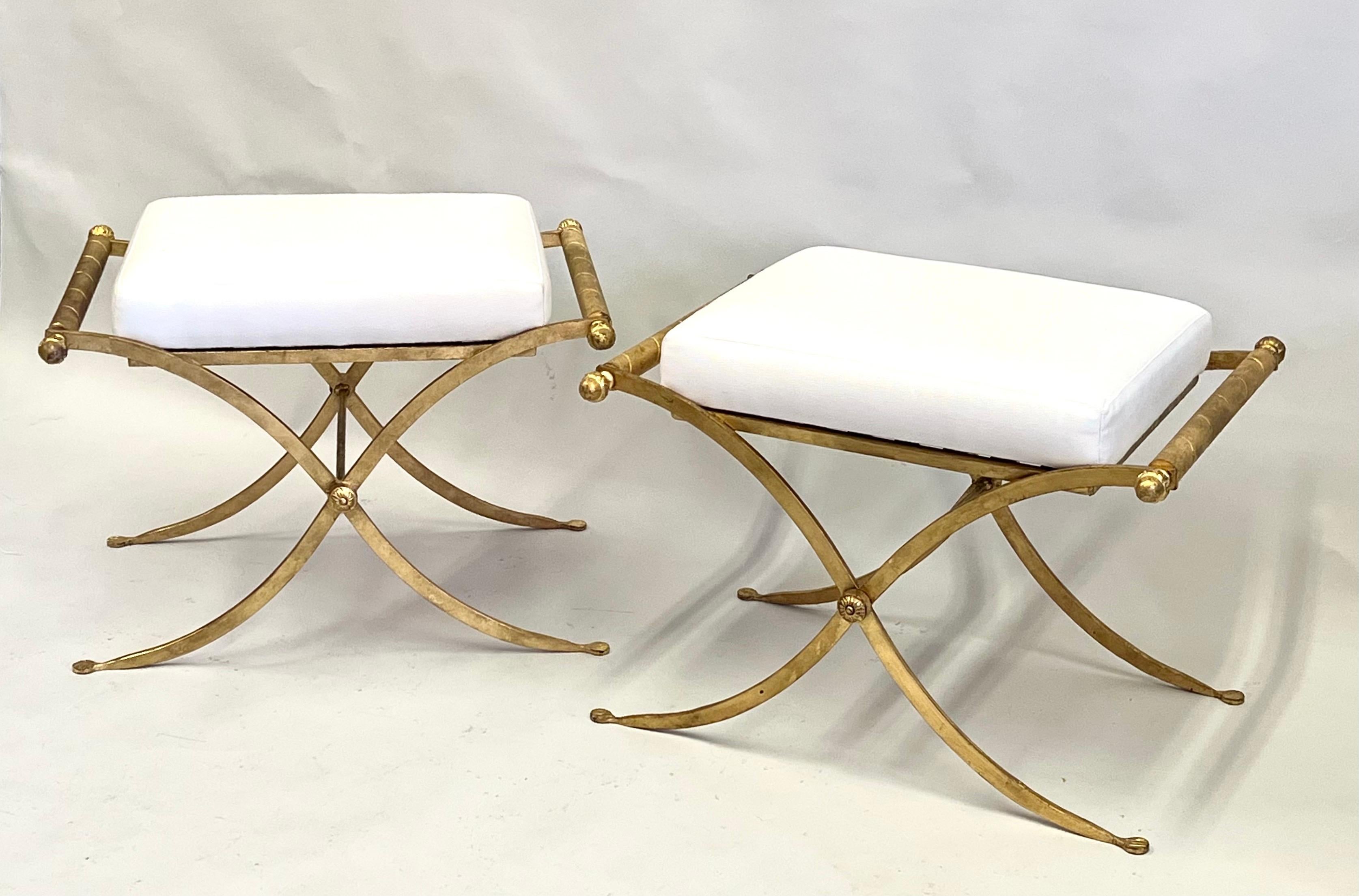 Elegant and Timeless Pair of French Midcentury Modern Neoclassical Benches or Stools Attributed to Raymond Subes circa 1930. The pieces are composed of hand gilt and hand wrought iron frames which support upholstered seats. The metal work is formed