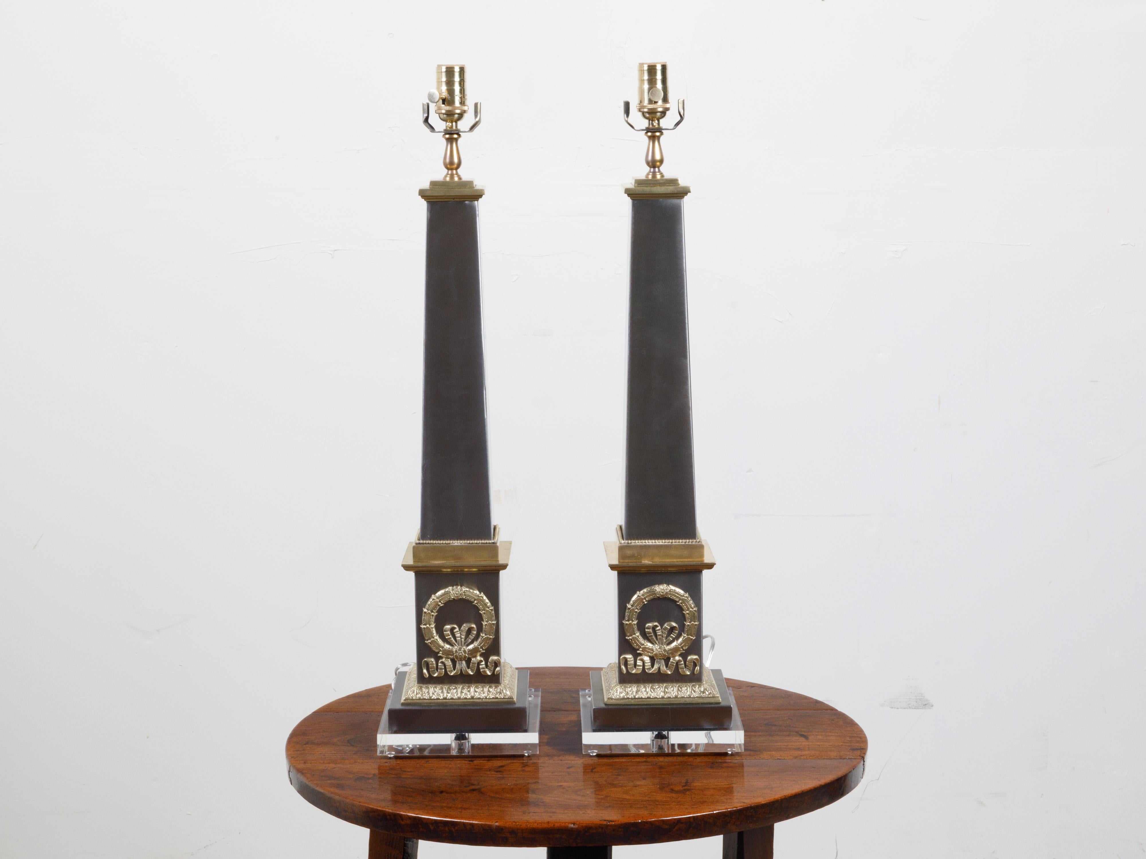 Une paire de lampes de table françaises en acier et laiton du milieu du 20e siècle, avec des bases en lucite. Créée en France au milieu du siècle dernier, cette paire de lampes de table présente un obélisque tronconique en acier orné d'une couronne