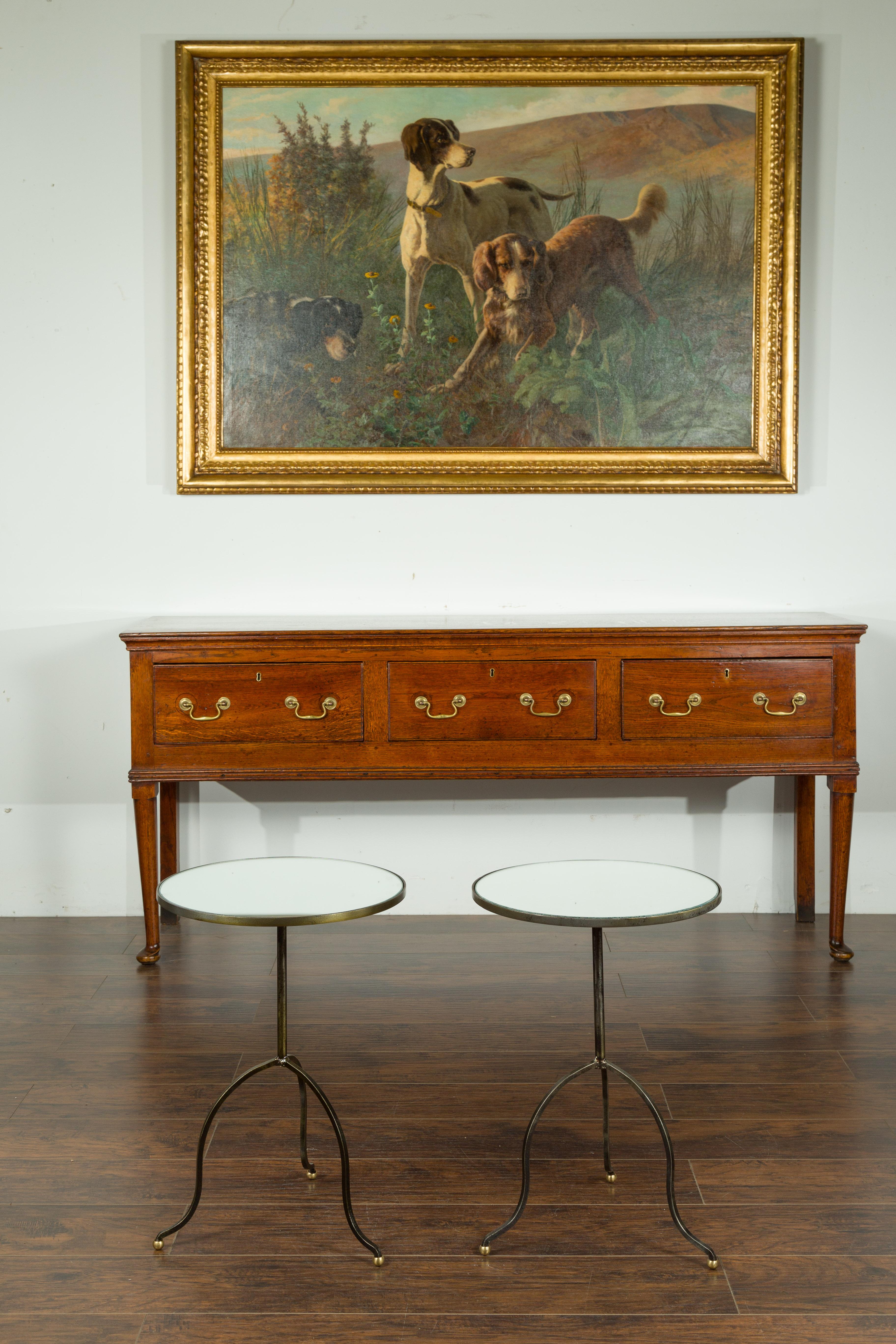 A pair of French vintage steel side tables from the mid-20th century, with mirrored tops.  Created in France during the midcentury period, this pair of small tables features a circular mirrored top resting on a pedestal. The ensemble is raised on a