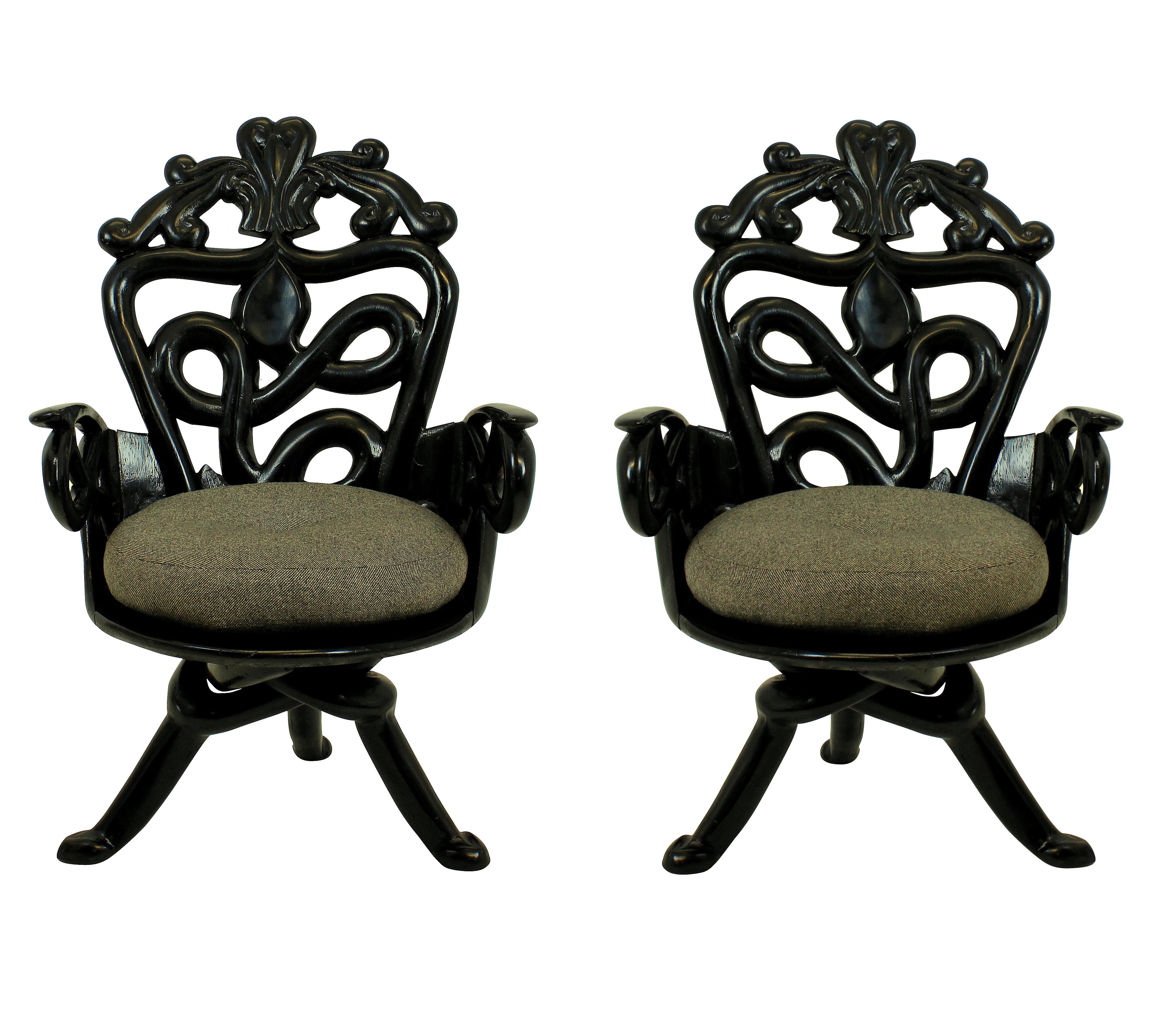A pair of French armchairs in the surrealist manner. Of florid design in ebonized solid teak with wool covered feather cushions. Of good heavy construction and surprisingly very comfortable.