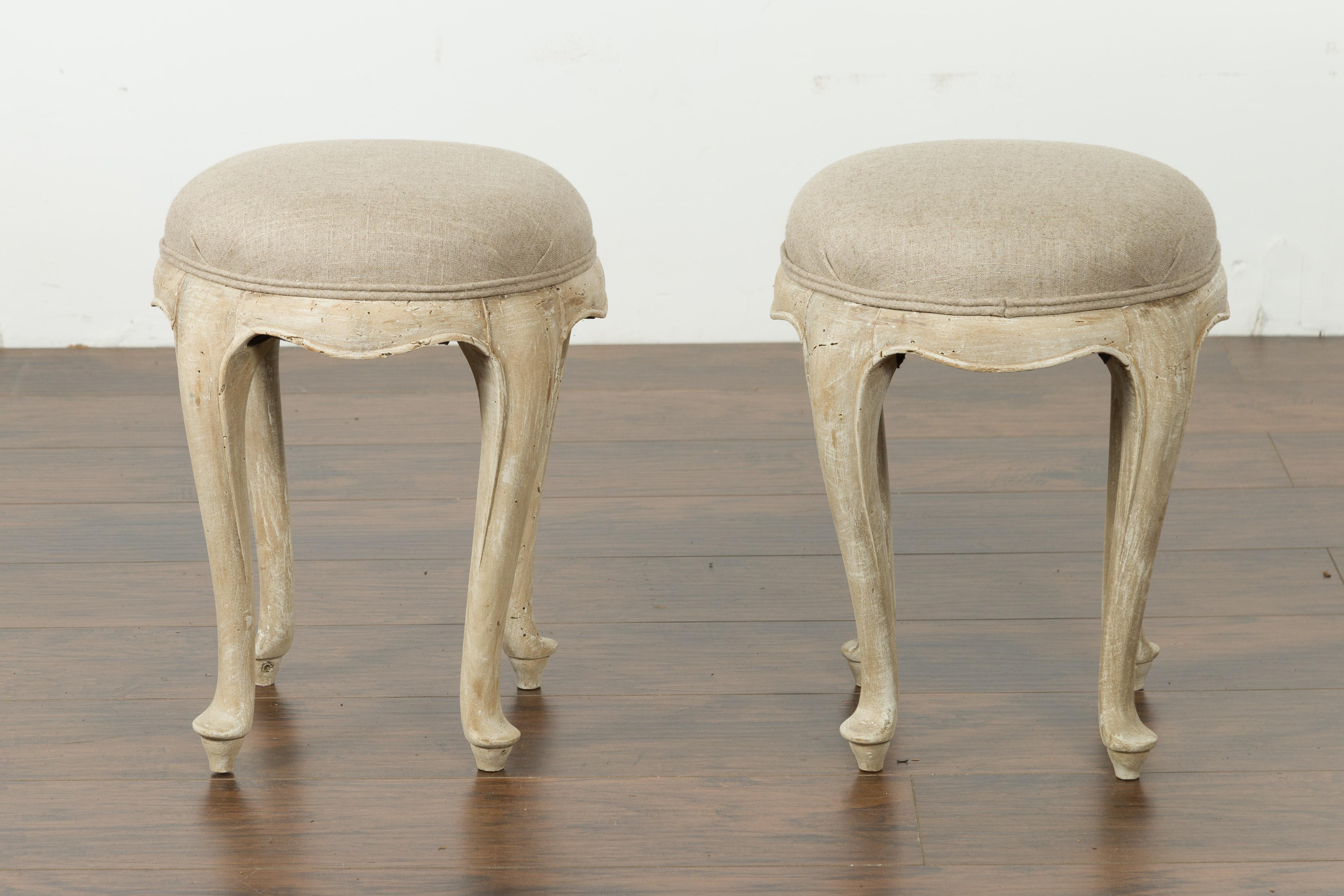 A pair of French Louis XV style walnut stools from the mid-20th century, with cabriole legs and new upholstery. Created in France during the midcentury period, each of this pair of Louis XV style stools features a circular seat newly recovered with