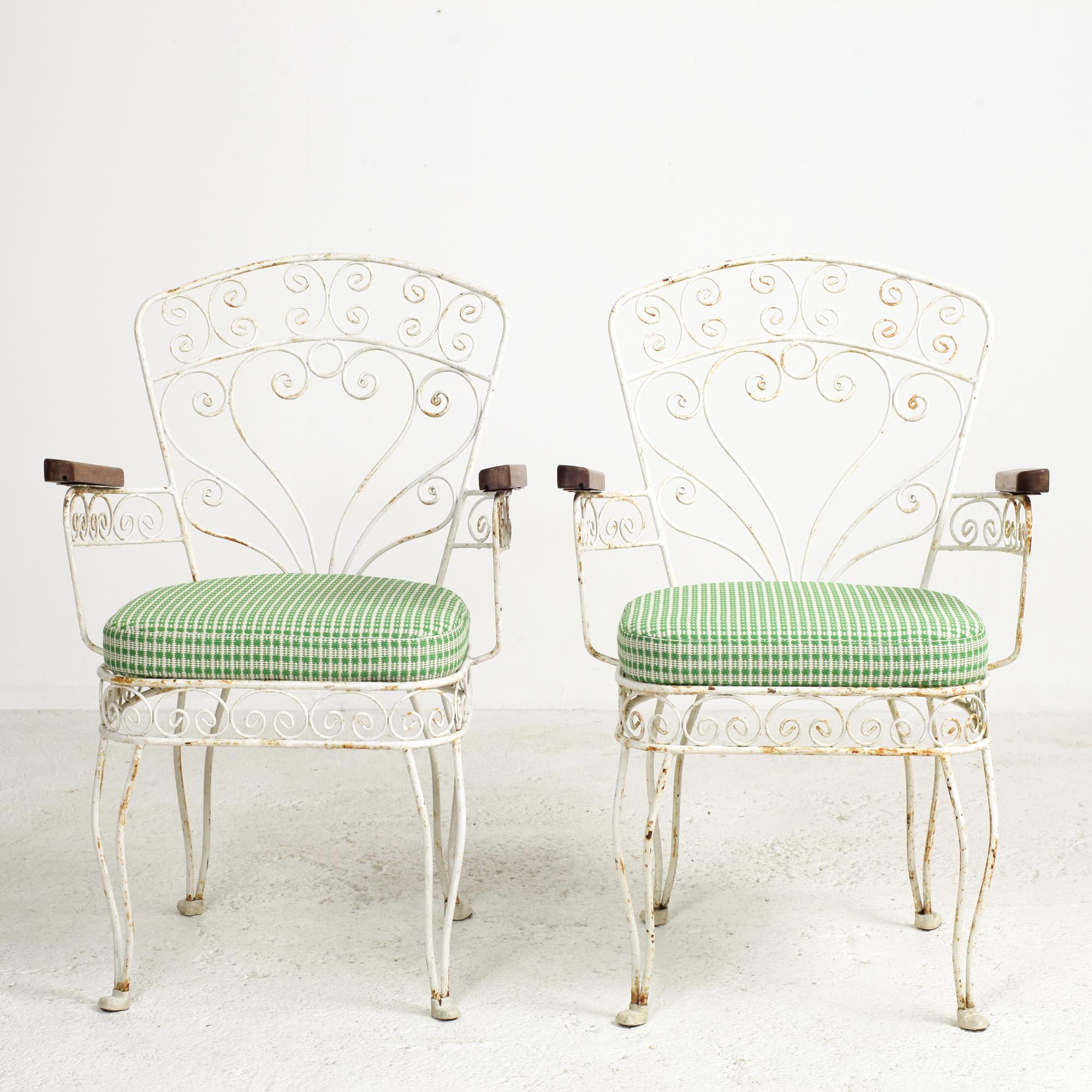Pair of French wrought iron and wire garden and patio armchairs. These pieces feature wrought iron frames with many ornamental wire trim adorned with arabesques, scrolls and solid oak armrests.
Original vintage condition, structurally sound and