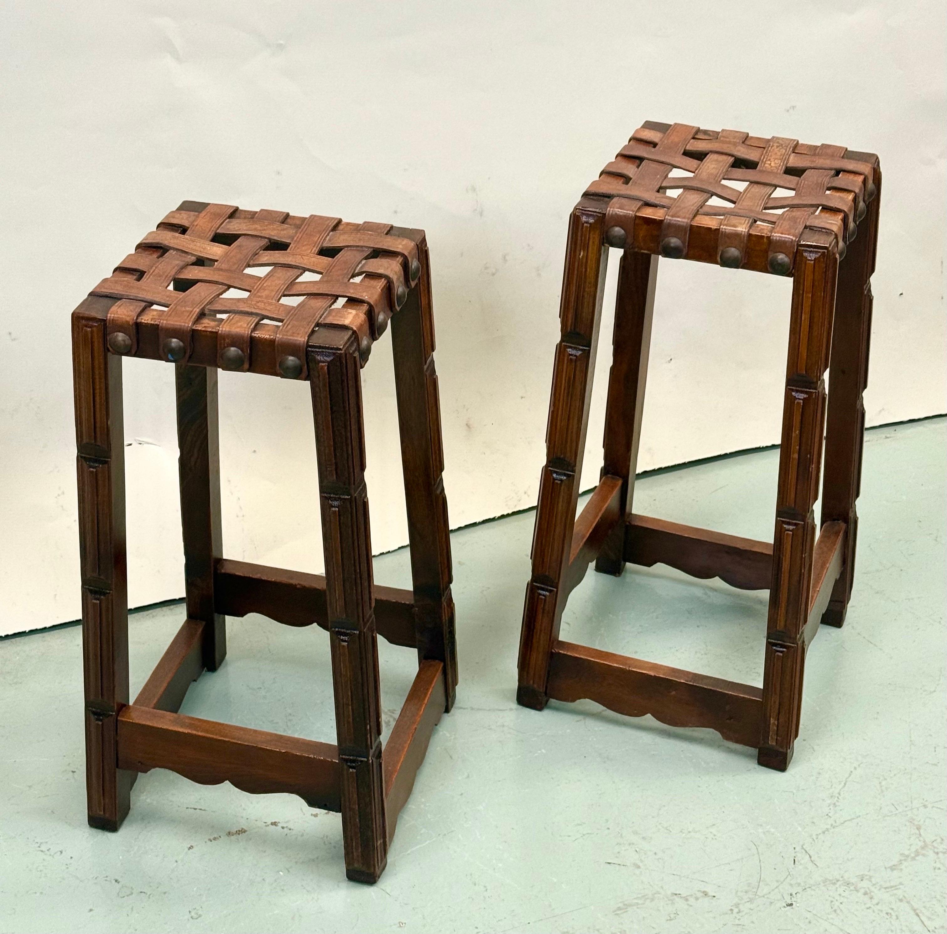 Paire de tabourets de bar artisanaux français du milieu du siècle, dans le style de Jean-Michel Frank, avec des bases en bois dur sculptées à la main et des sièges composés de lanières de cuir entrelacées, vers 1940. Ces pièces rares et