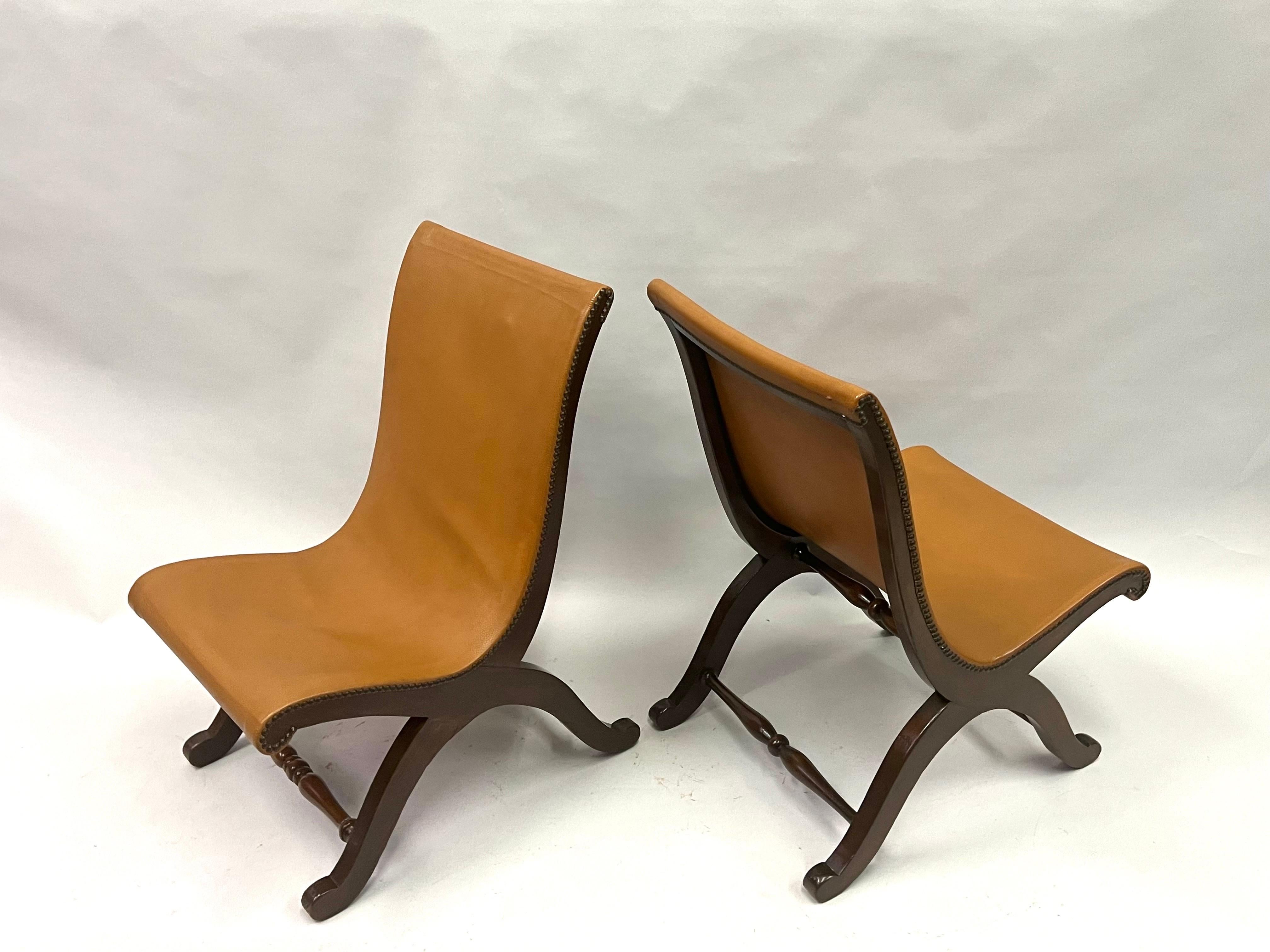 An Elegant and Timeless Pair of French Mid-Century Modern Neoclassical Lounge or Slipper Chairs in a solid hardwood frame and covered in a glove-like leather. These chairs are derived from neoclassical design ideas that are several centuries old.