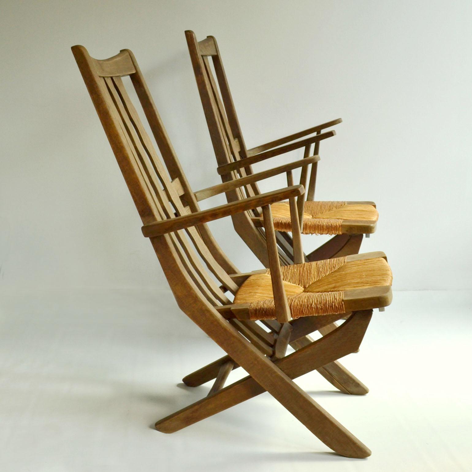 A pair of adjustable oak outdoor of garden chairs in the French modernist style of the 1950's. The reed seated chairs can be adjusted in three comfortable positions; upright, relaxed and reclining similar to the deck chairs. The positioning is easy