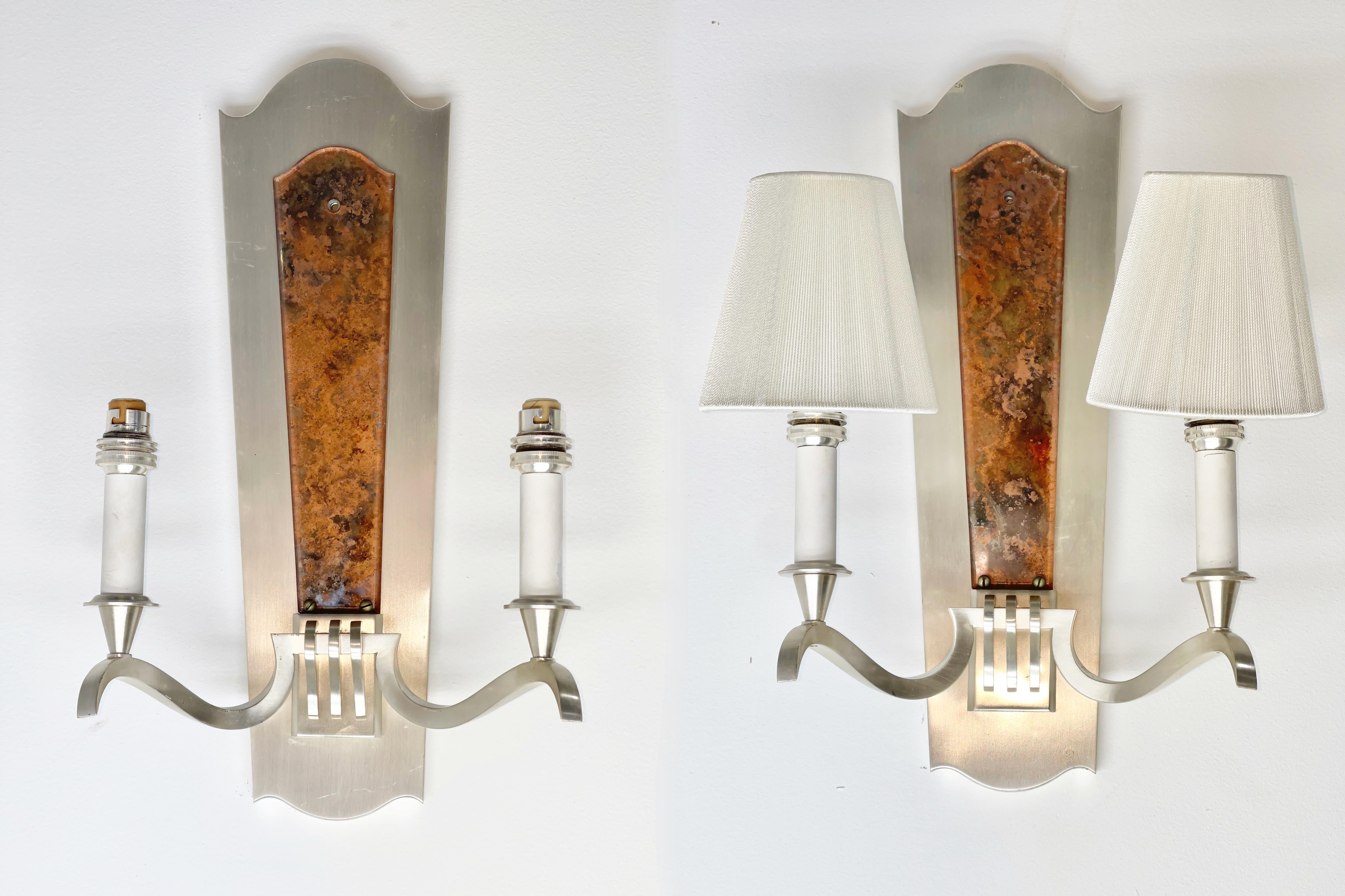 Pair of French modernist wall sconces in brushed nickel plating with a faux eglomise beveled acrylic panel on the face of the backplate, attributed to Genet et Michon.
Dimensions shown are for sconce without shades.
Shades shown for display purposes