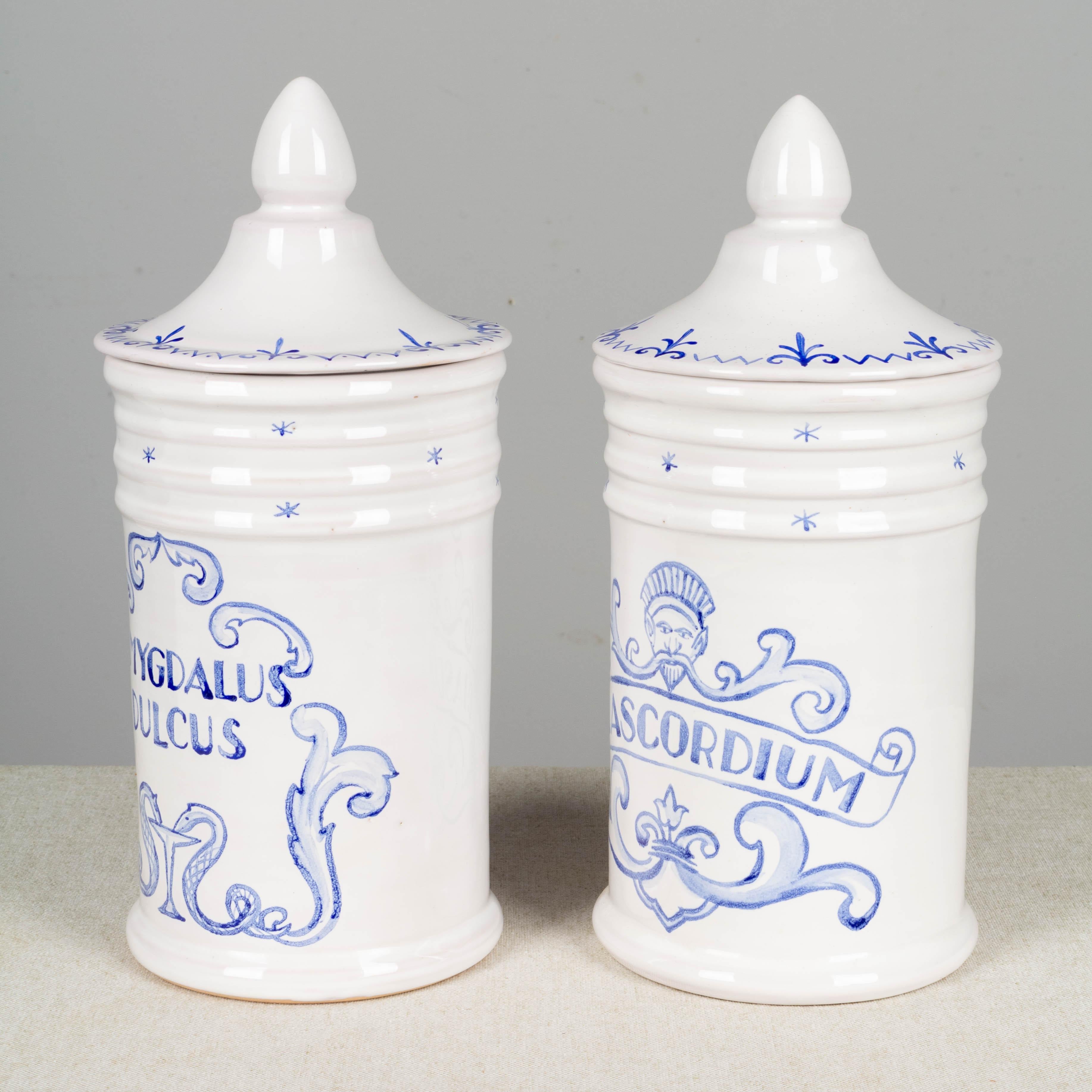 A pair of French Moustiers white glazed ceramic lidded apothecary jars with pale blue hand painted decoration. One is labeled Amygdalus Dulcus and the other labeled Diascordium. Marked on underside: Garnier Moustiers