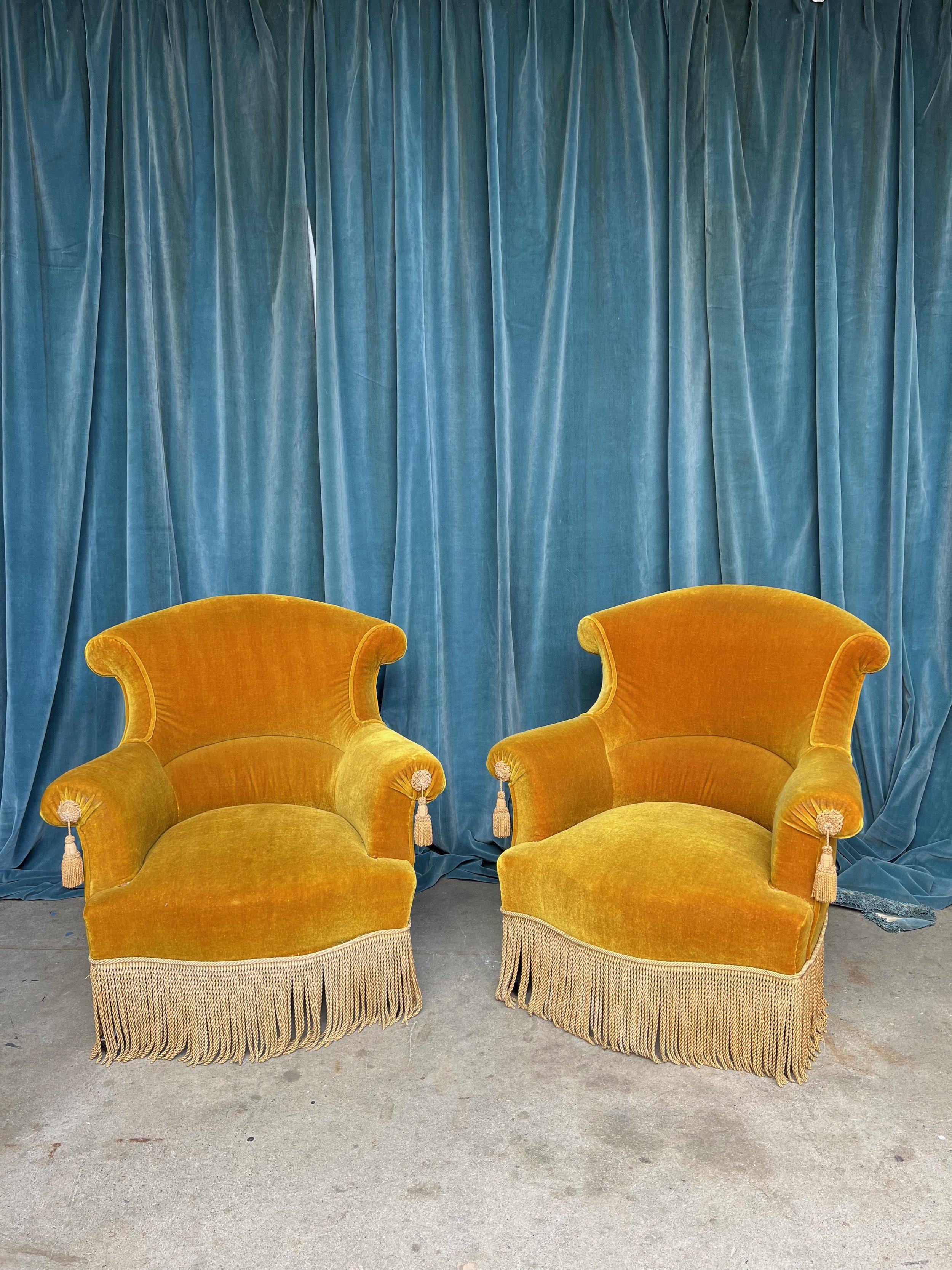 A stunning pair of French Napoleon III armchairs. These French 19th century Napoleon III armchairs are simply beautiful. Upholstered in a rich gold velvet with contrasting bullion fringe and tassels, they are the very definition of luxurious. The