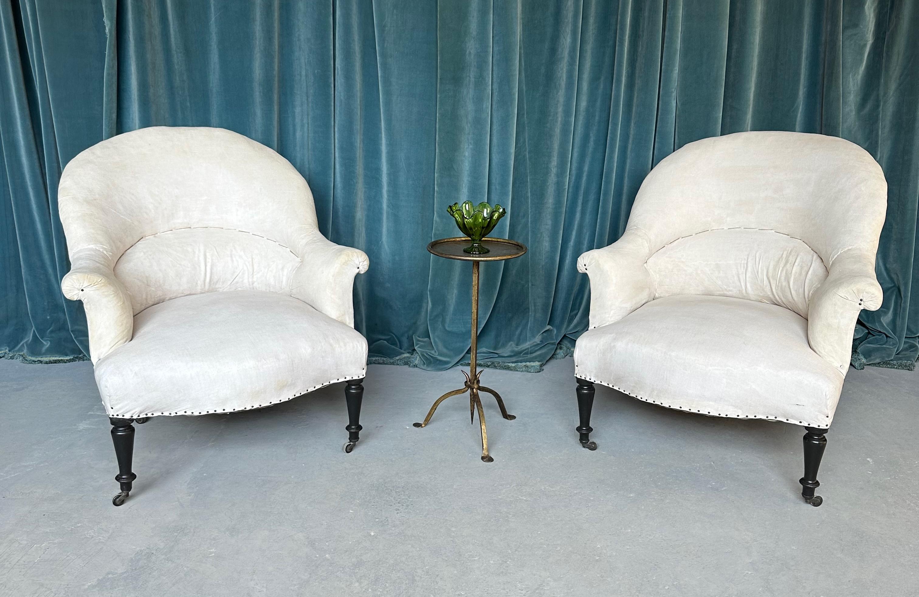 A classic pair of French 19th century Napoleon III style armchairs with gracious rounded backs and gently flared arms. These chairs are designed with impeccable proportions, featuring a generously curved back that offers outstanding lumbar support