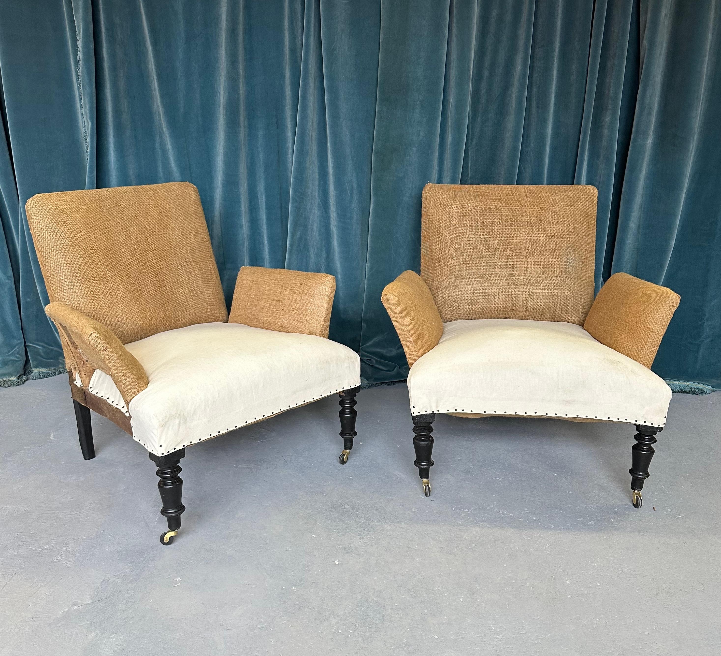An interesting pair of French late 19th century armchairs that have been stripped down to the burlap and muslin and are ready to be upholstered. This unusual pair of period armchairs features rectangular backs as well as rectangular arms that are