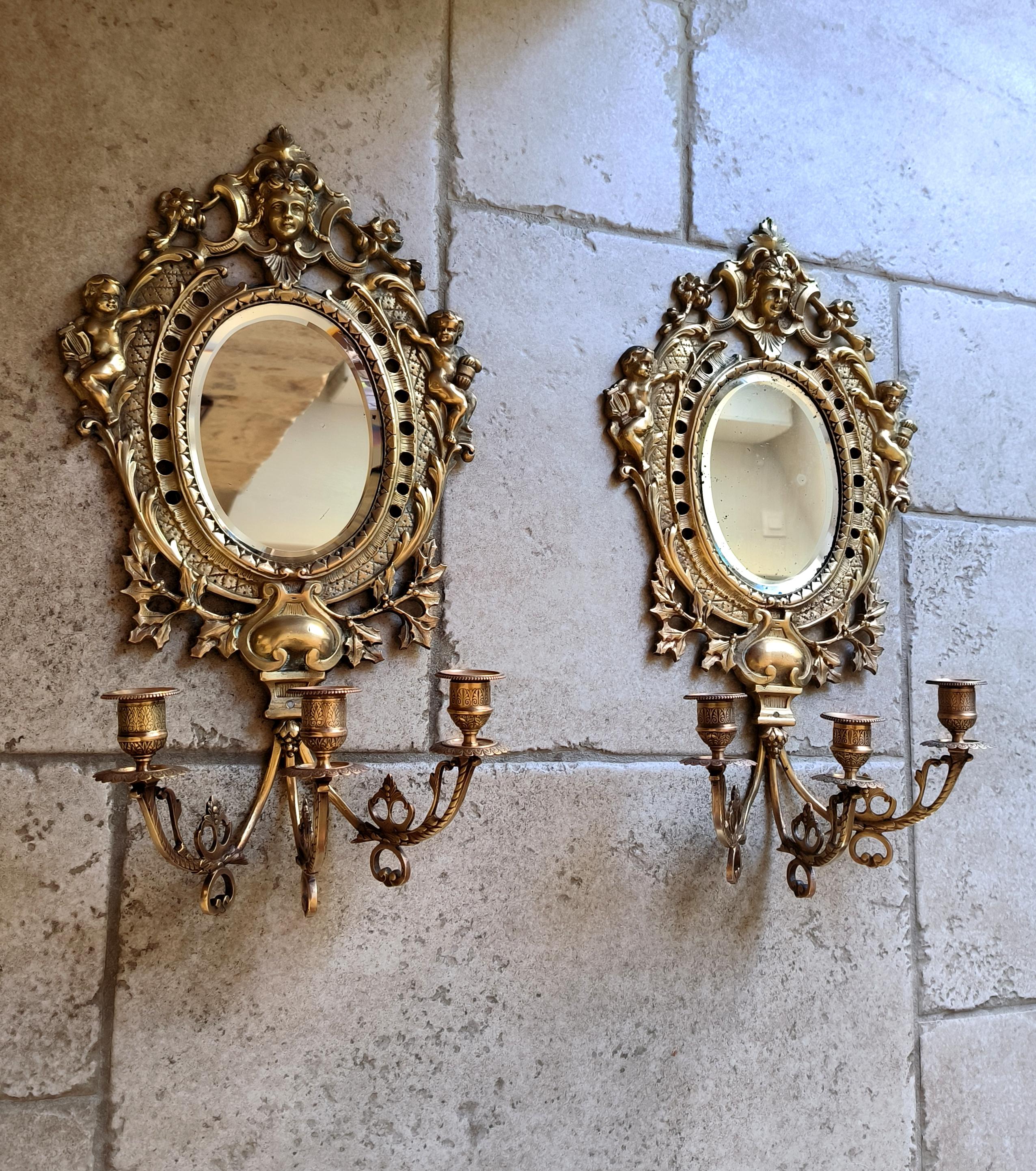 Questa splendida coppia di antiche appliques a specchio francesi, Napoleone III, in bronzo massiccio, raffiguranti cherubini e Mascaron stilizzati, forse di Marianna, fanno sicuramente colpo su qualsiasi parete. La qualità, il peso e i dettagli