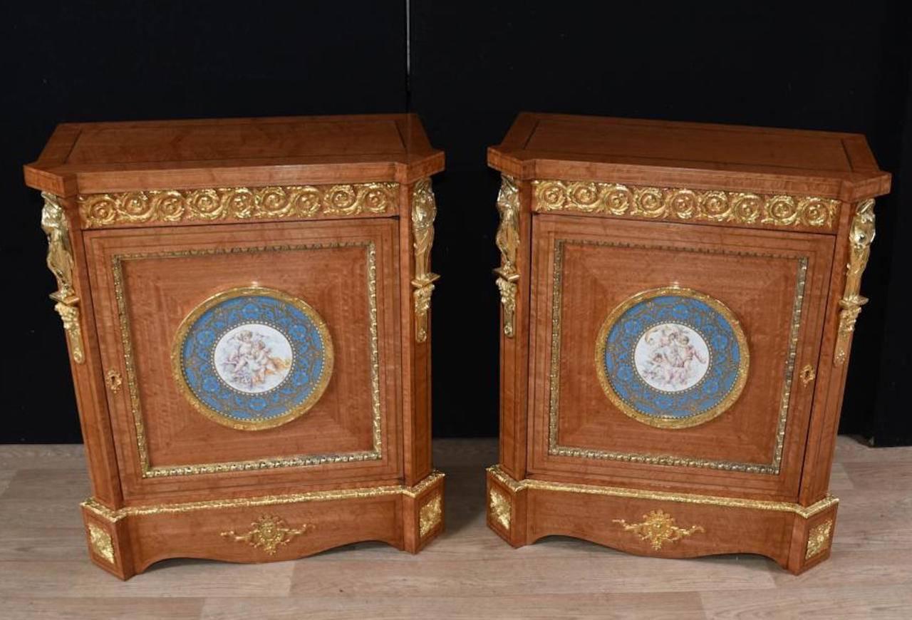 A pair of French Napoleon III, satinwood side cabinets, circa 1910. Adorned with fine quality ormolu mounts. Each centre panel contains a Sevres porcelain plaque depicting cherubs surmounted in a round elaborate ormolu frame.
 