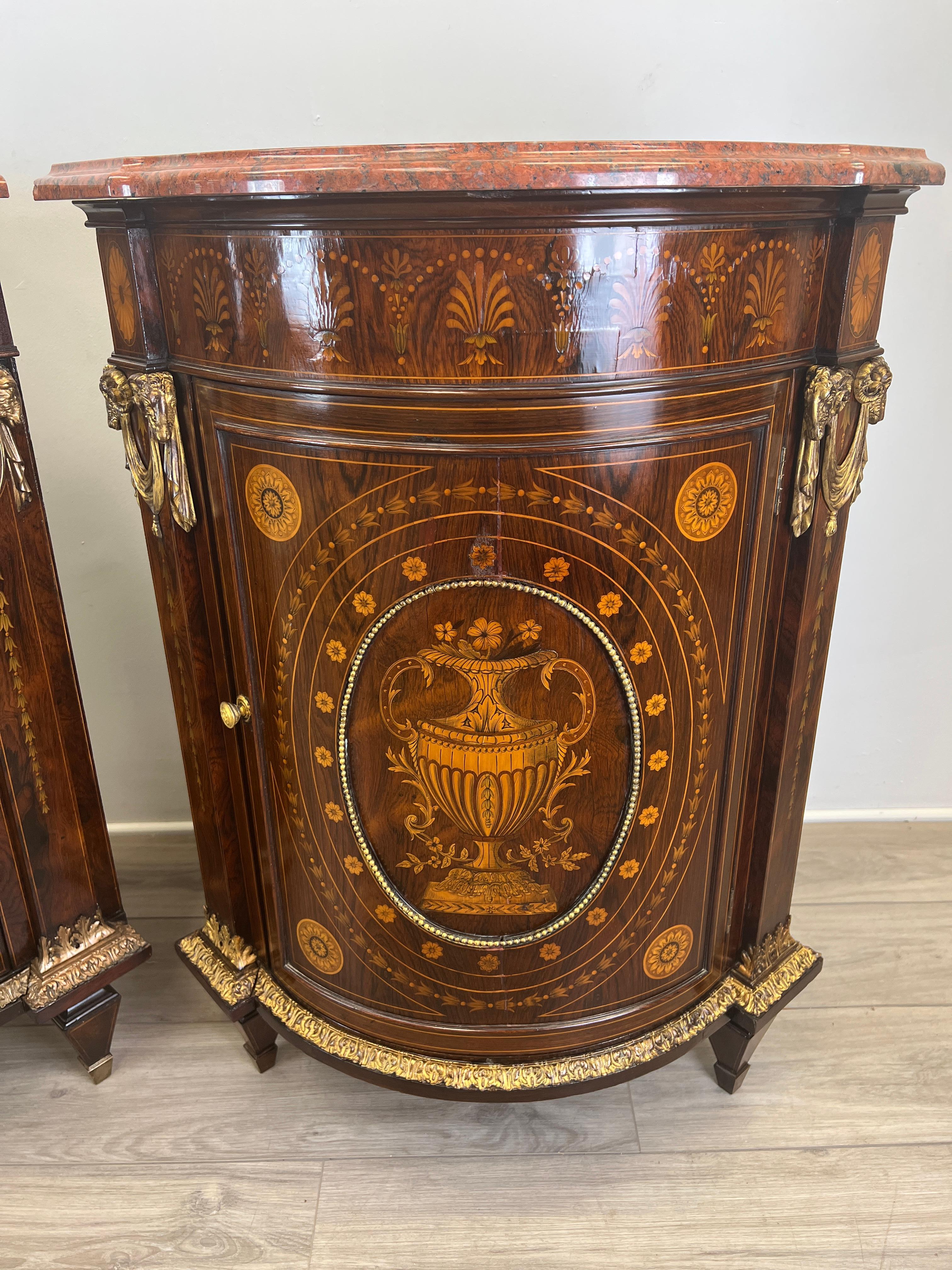 Featured is a pair of French Napoleon III neo classical Encoignure cabinet's in rosewood mounted with gilt bronze foliate and heavily inlaid with neoclassical themes throughout. The cabinets themselves are decorated with palmetto inlay patterns of