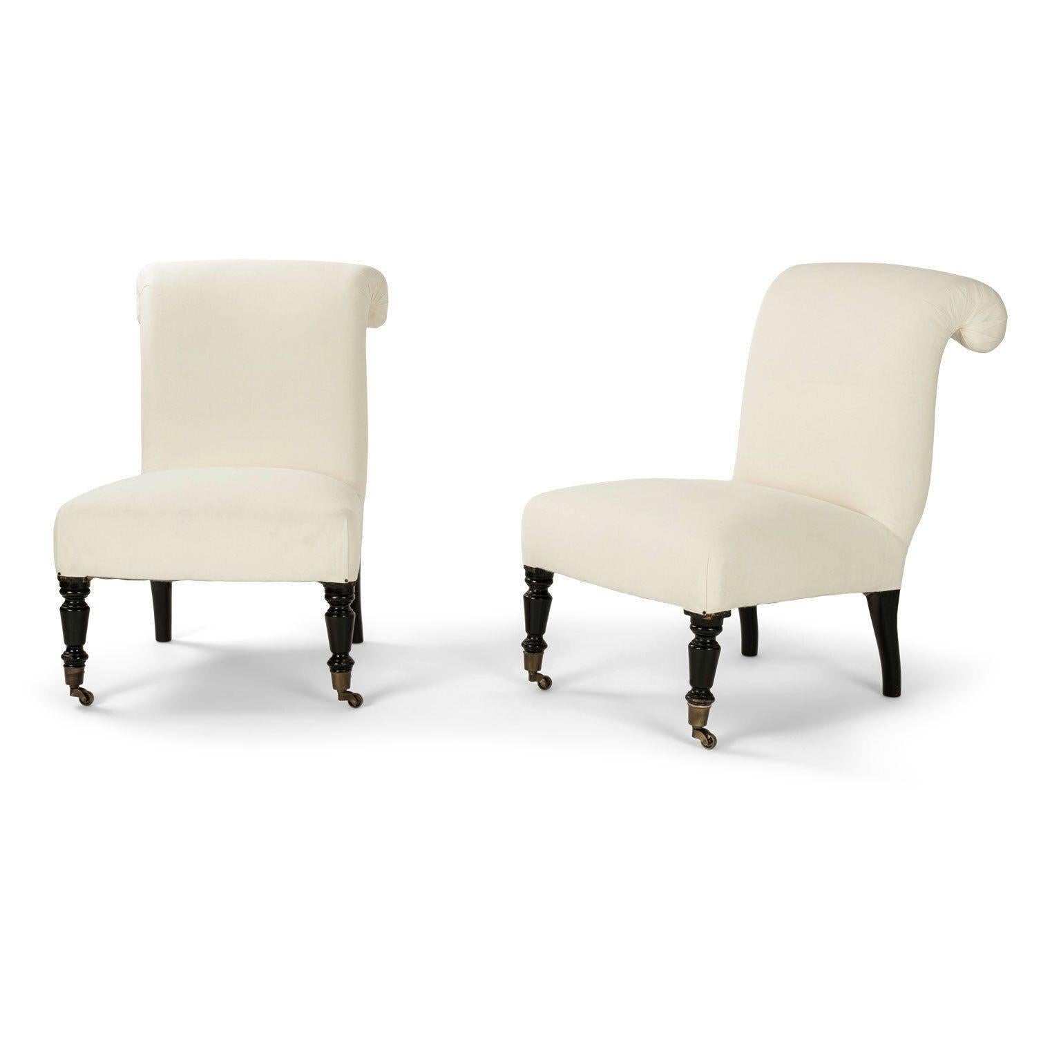 Pair of French Napoleon III slipper chairs circa 1870-1890. Newly upholstered in off-white muslin. Ebonized legs. Later brass casters on front legs. Two available and sold together as a pair priced $5,200.