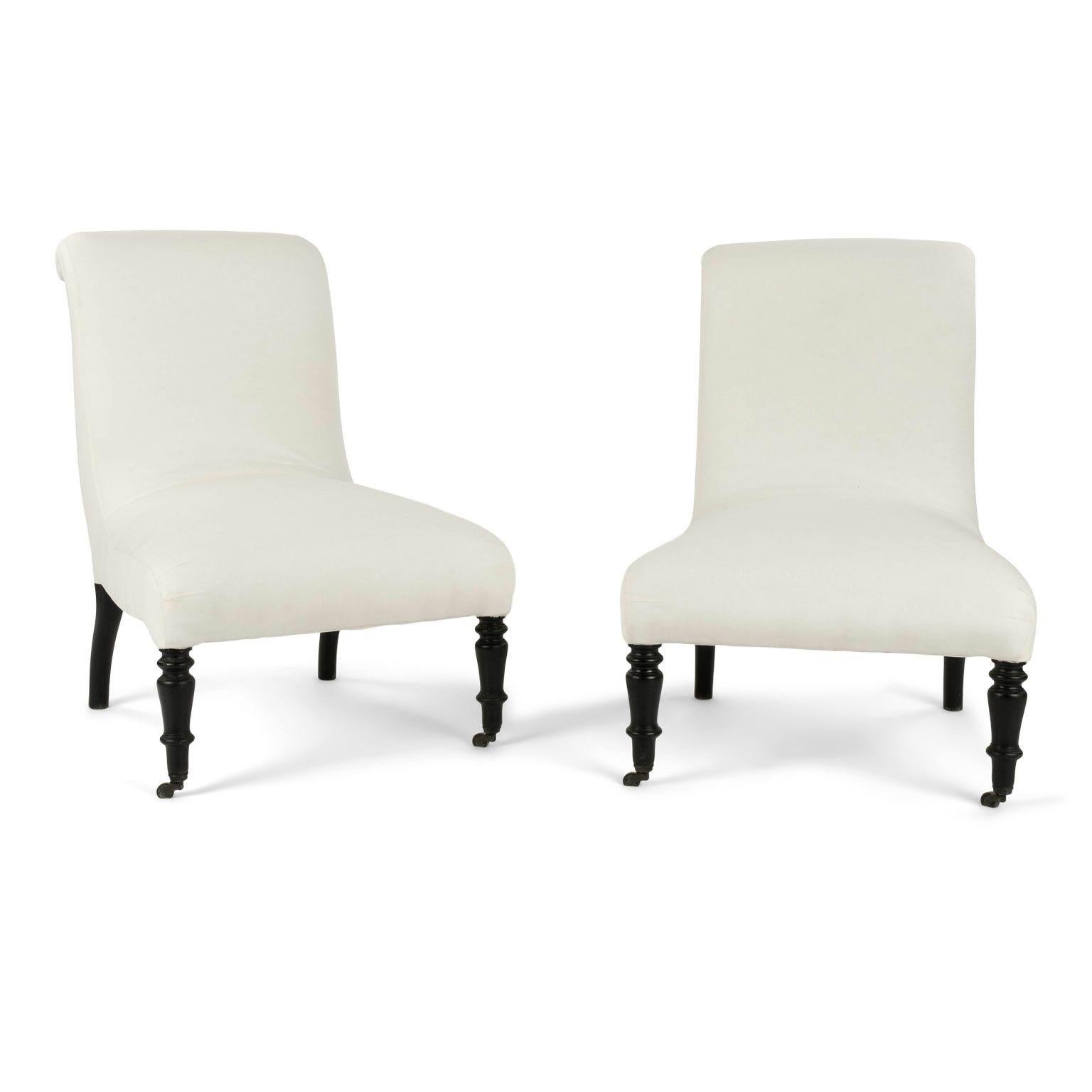 Pair of French Napoleon III slipper chairs circa 1870-1890. Newly upholstered in off-white muslin. Ebonized legs. Later brass casters on front legs. Two available and sold together and priced $5,600 for the pair.