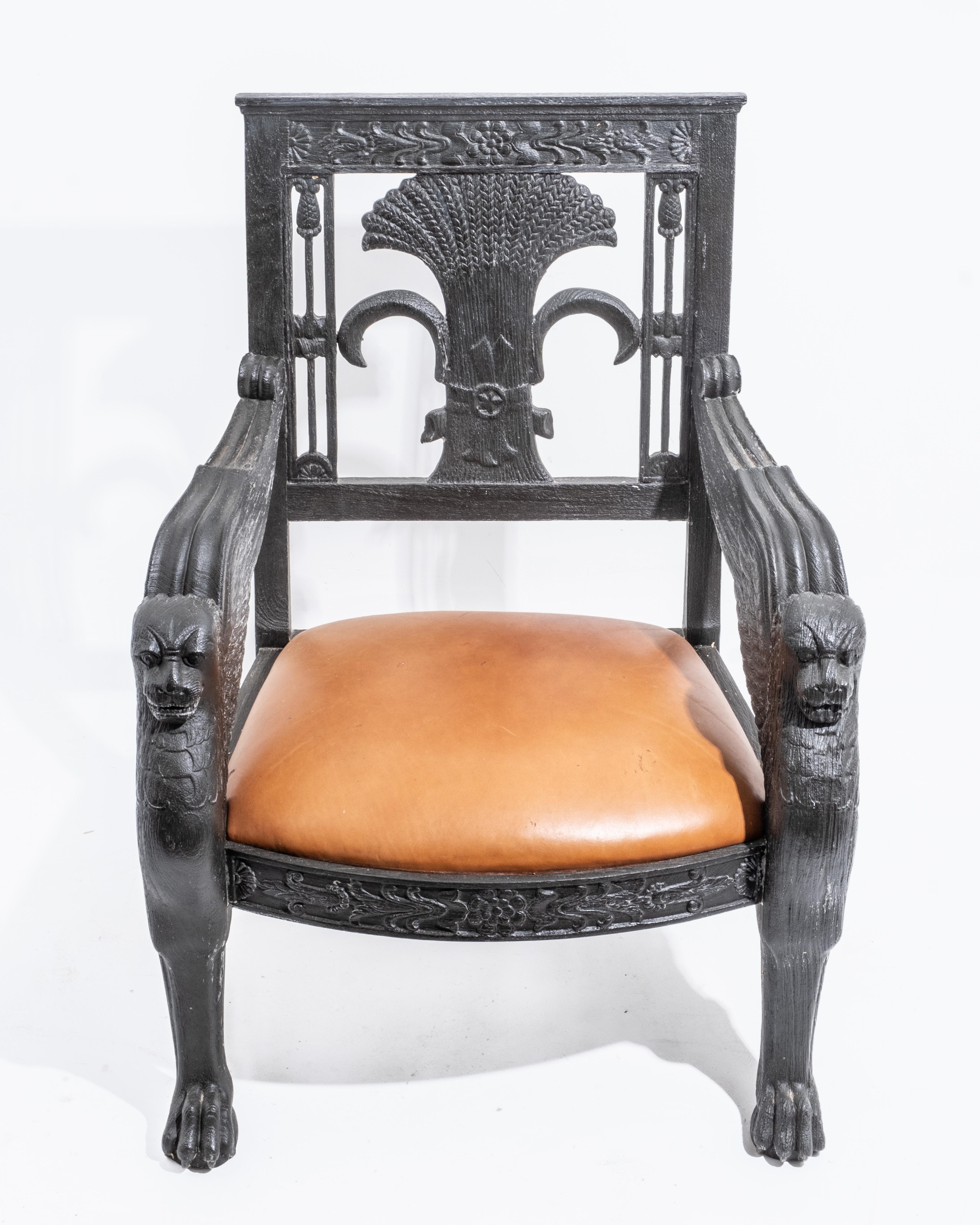 Coppia di poltrone antiche francesi in stile napoleonico con intagli ornamentali e finitura in legno ebanizzato. Le sedie sono progettate come troni e presentano elaborate figure di leoni alati sui braccioli che aggiungono un fascino regale e