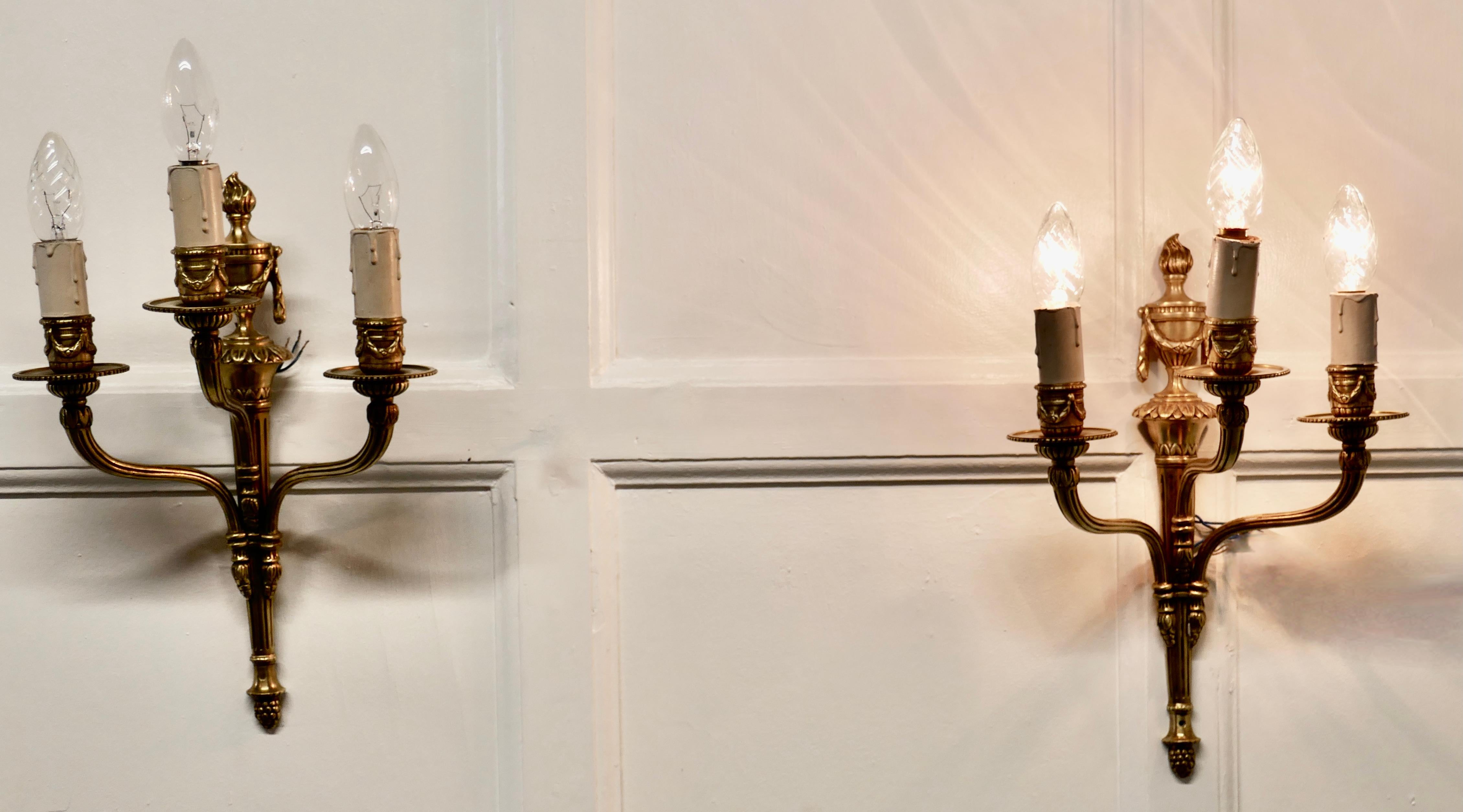 Pair of French neoclassical brass triple wall lights


A very handsome pair of brass wall lights, the lights are in the classical style of a lighted torch
Each light has 3 branches each with a sconce and candle tube
The lights have been