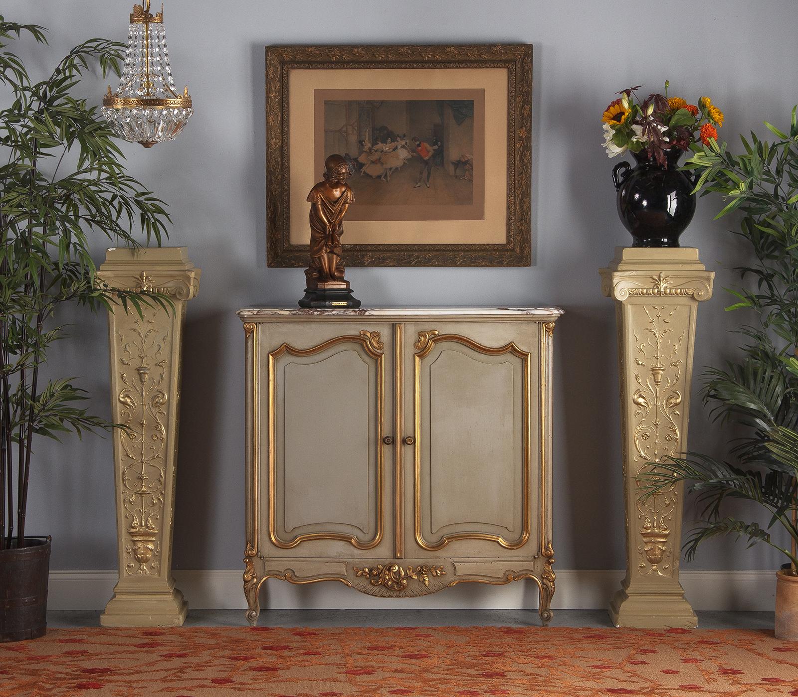 A very decorative pair of French pedestals made of painted and gilded plaster, circa 1940s. The style mixes neoclassical, Second Empire and Louis XVI. The pedestals are painted in yellow-green tones with gilded motifs of urns, arabesques and birds.