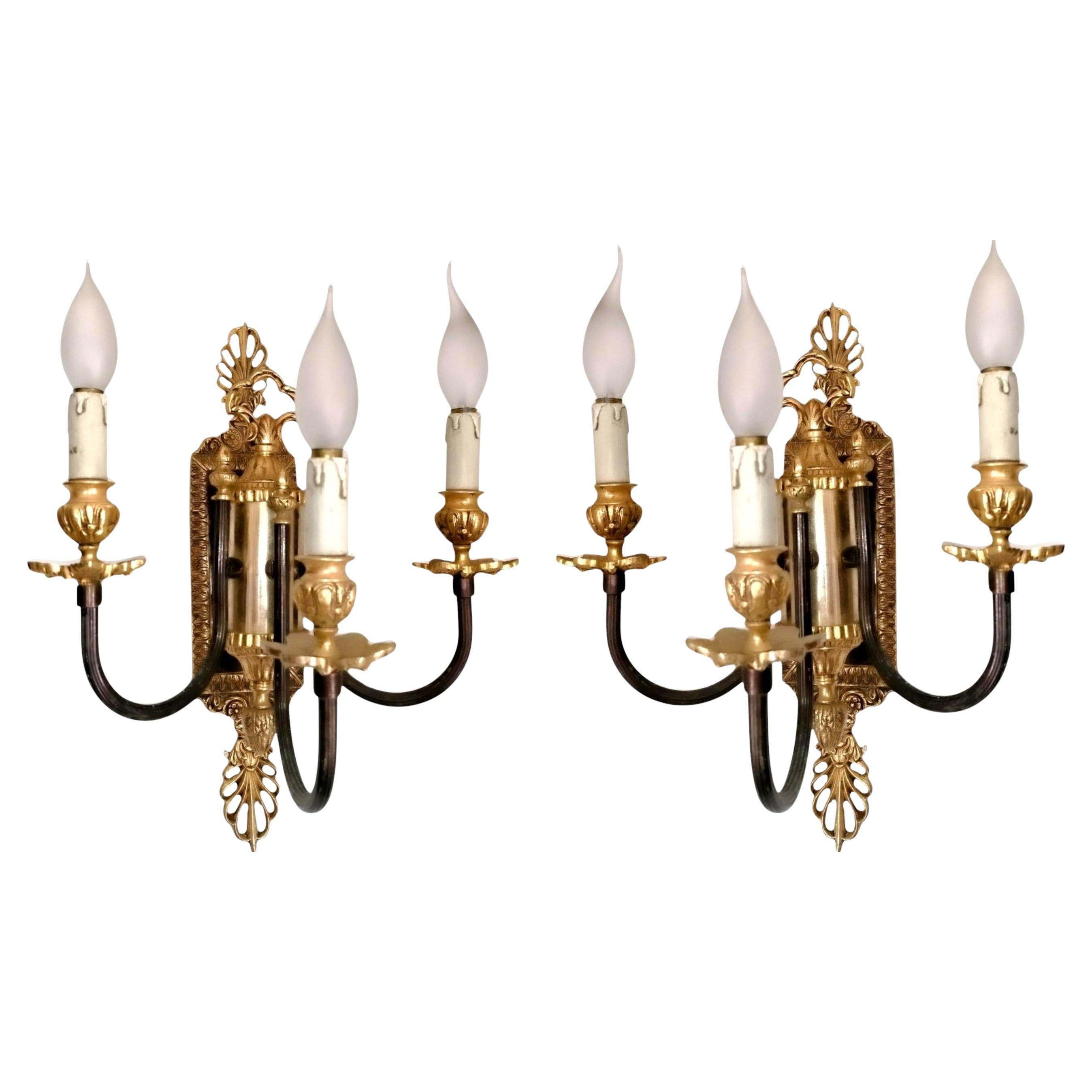  Elegante y refinado par de apliques neoclásicos franceses de tres brazos cada uno, fabricados en bronce patinado con detalles en bronce dorado de 24 quilates.
Estos exquisitos apliques muestran motivos clásicos atemporales y una ornamentación