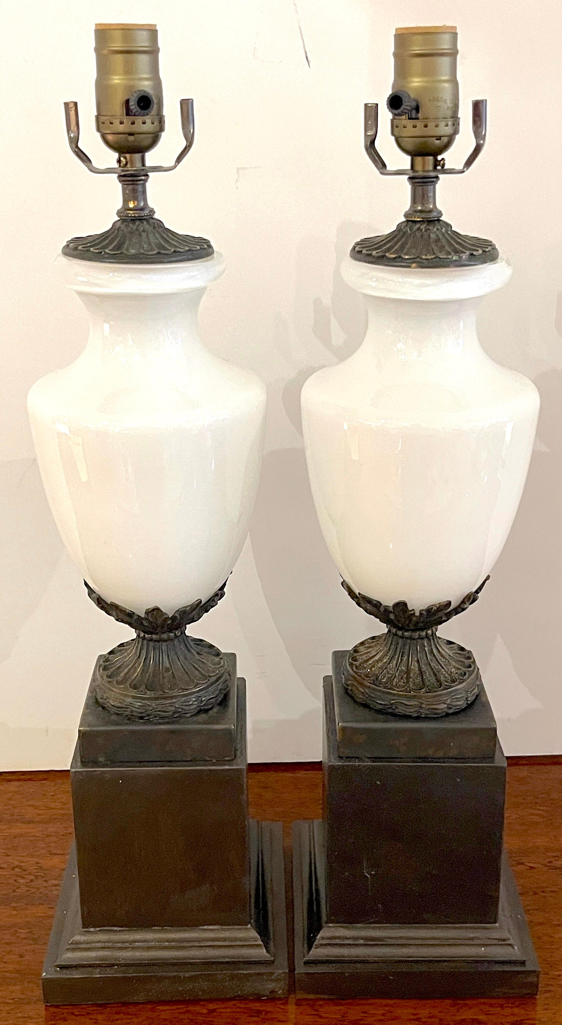Pair of French neoclassical bronze mounted opaline vases, now as lamps
France, 20th century
Each one with a white opaline glass urn of typical form with cast and patinated acanthus motif mounts raised on ebonized pedestal bases. New