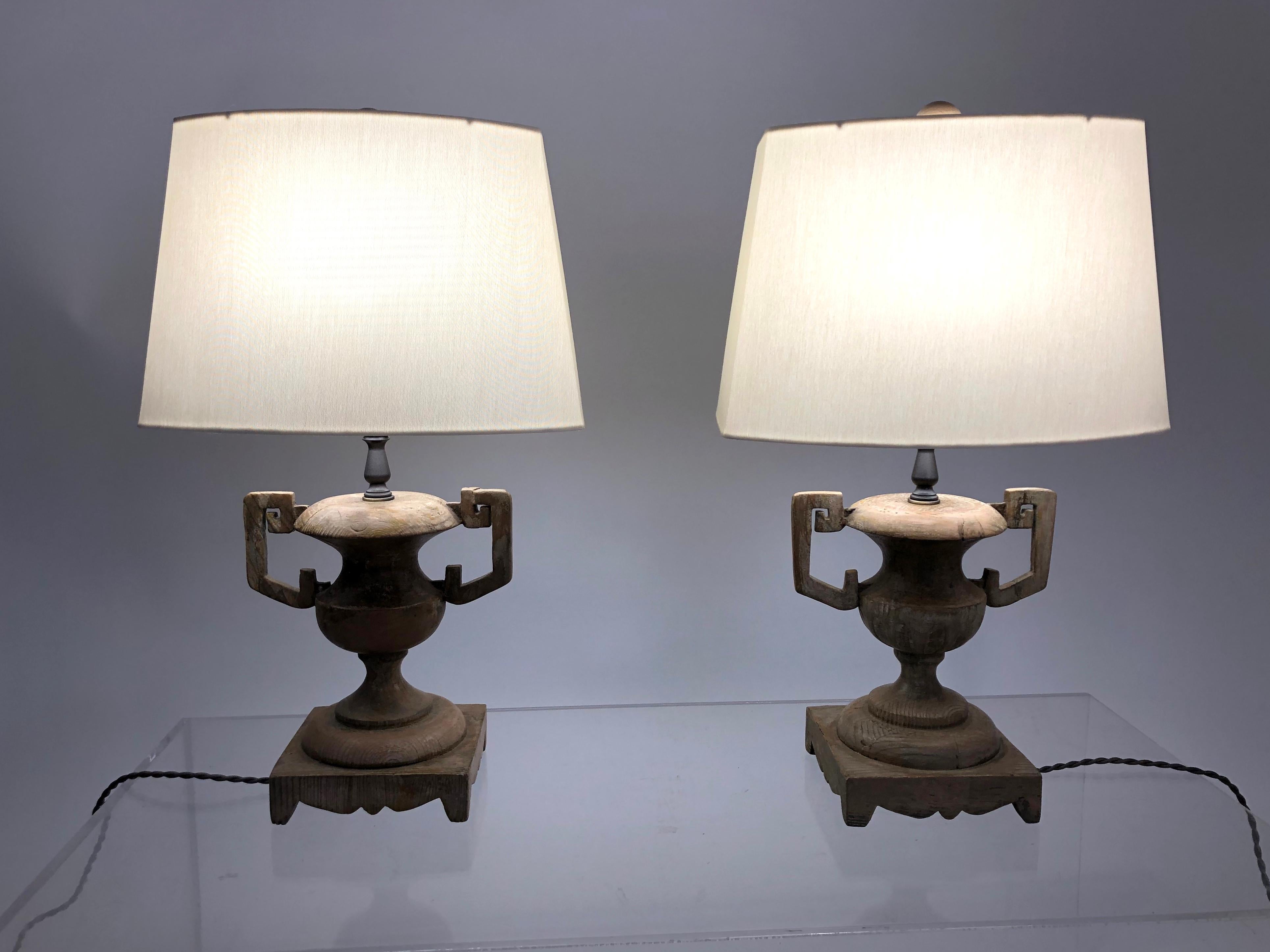 A stylish pair of French carved wood urn-form lamps, with geometric strap handles on scalloped square bases, with new shades and finials. Newly electrified.
Perfect for bedside tables, a console table or ambient lighting in a variety of