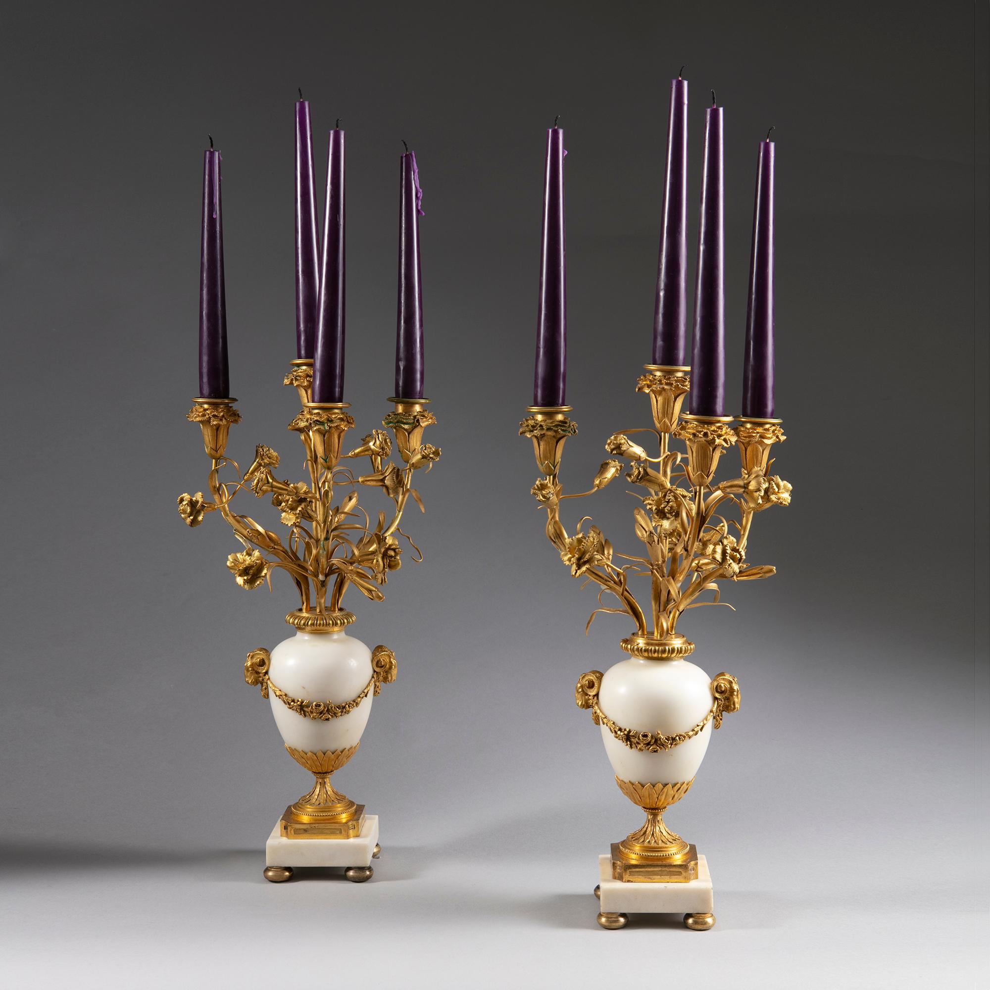 Pair of late 19th century neoclassical ormolu gold and white marble candelabra

Each with four arms issuing from gilt bronze carnation flowers

Raised on classical white marble bodies with classical gilt bronze mounts

Rams heads symbolise
