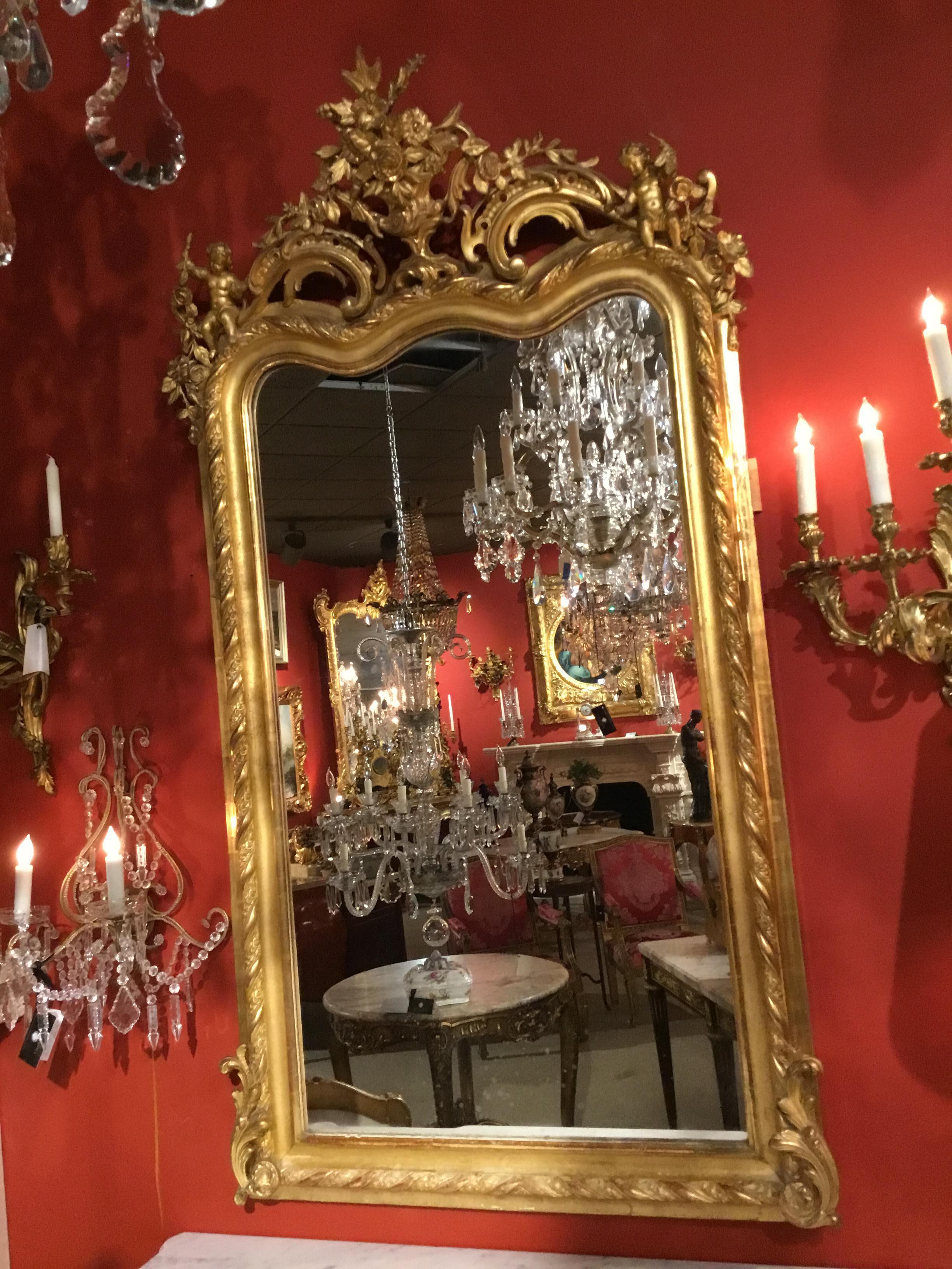Giltwood French mirrors with a carved urn filled with a floral bouquet
Gilt putti adorn each of the upper corners. A roped design is draped
Down the sides and the bottom of these mirrors. It is rare to find two
Matching pieces like this.